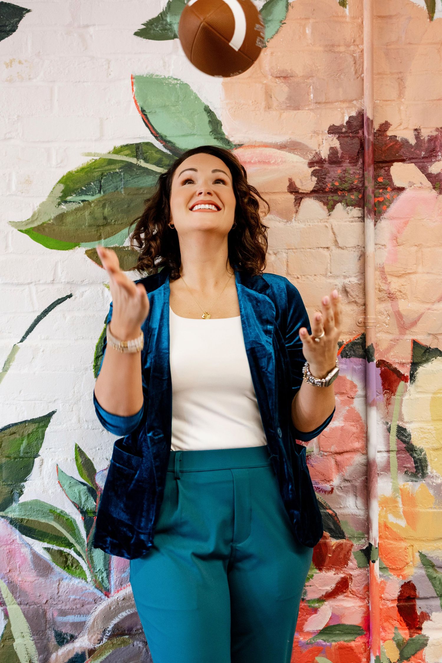 Creative portrait against colorful floral mural wall wearing navy blue outfit.