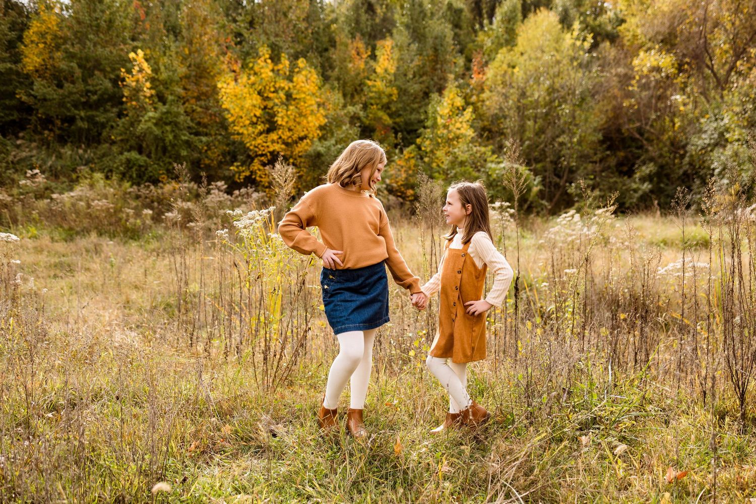 A group relaxes together in a sunlit autumn meadow with golden grass and trees in the background.
