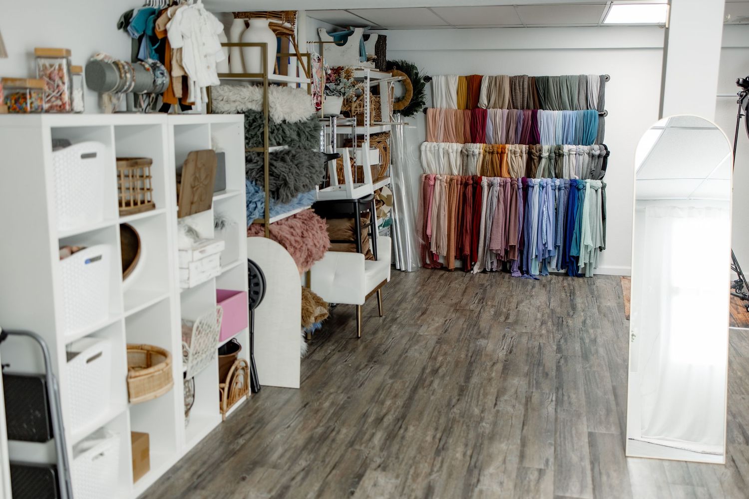 Bright and airy walk-in closet with gray wood flooring, white built-in shelving, and organized clothing storage.