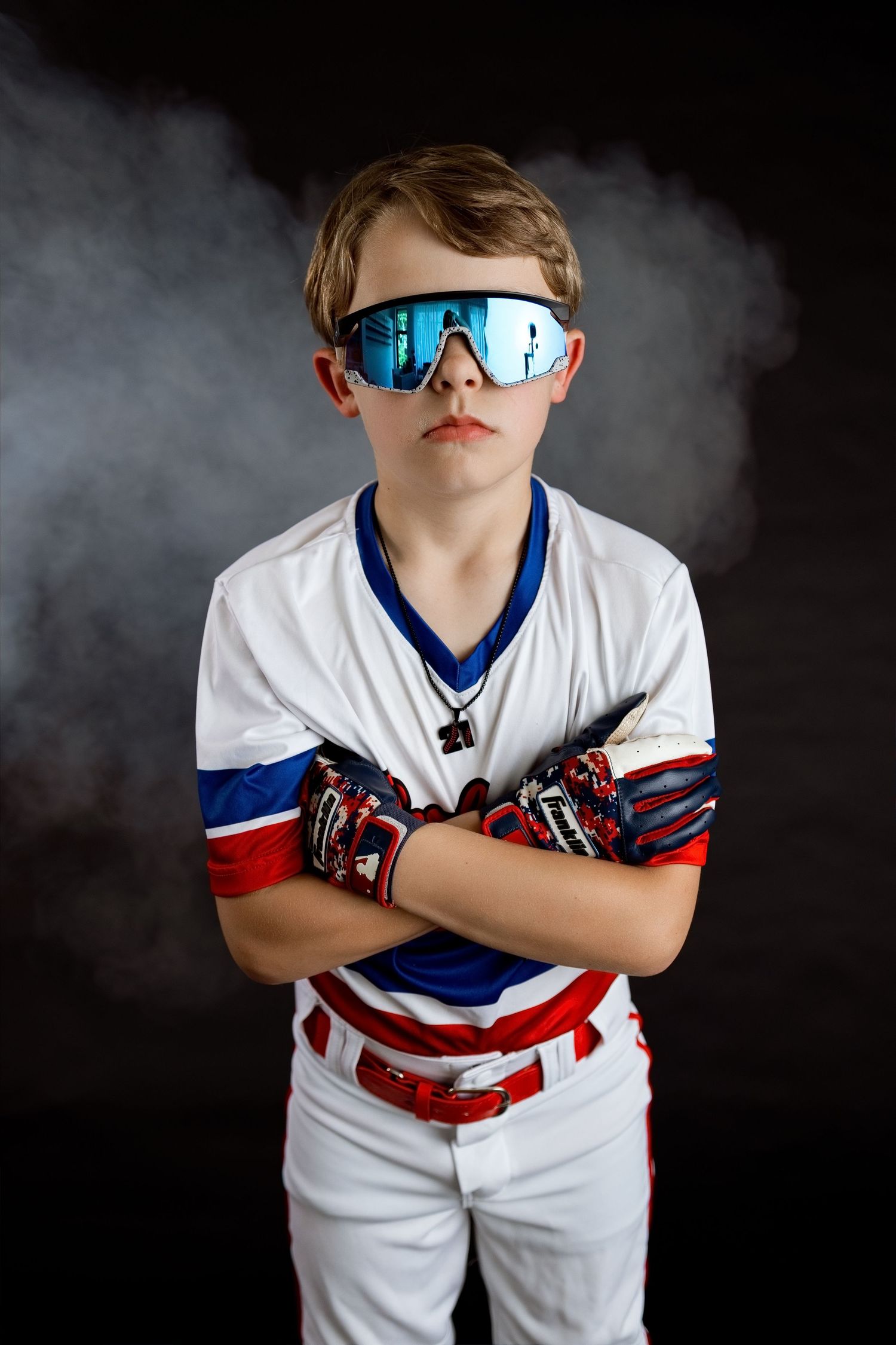 Youth baseball player standing confidently with crossed arms during a creative studio sports portrait session
