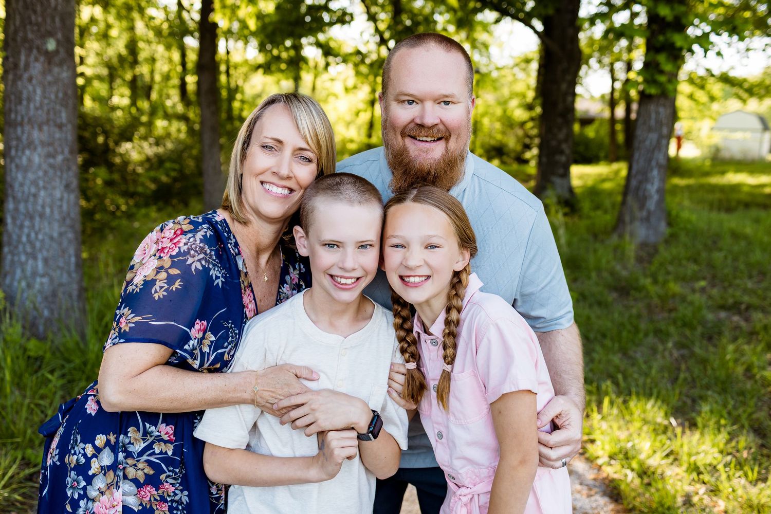 A family shares warm smiles while posing together on a nature path.
