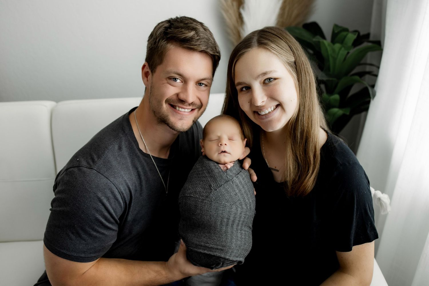 Family portrait session in bright modern studio with grey and white decor and indoor plants.