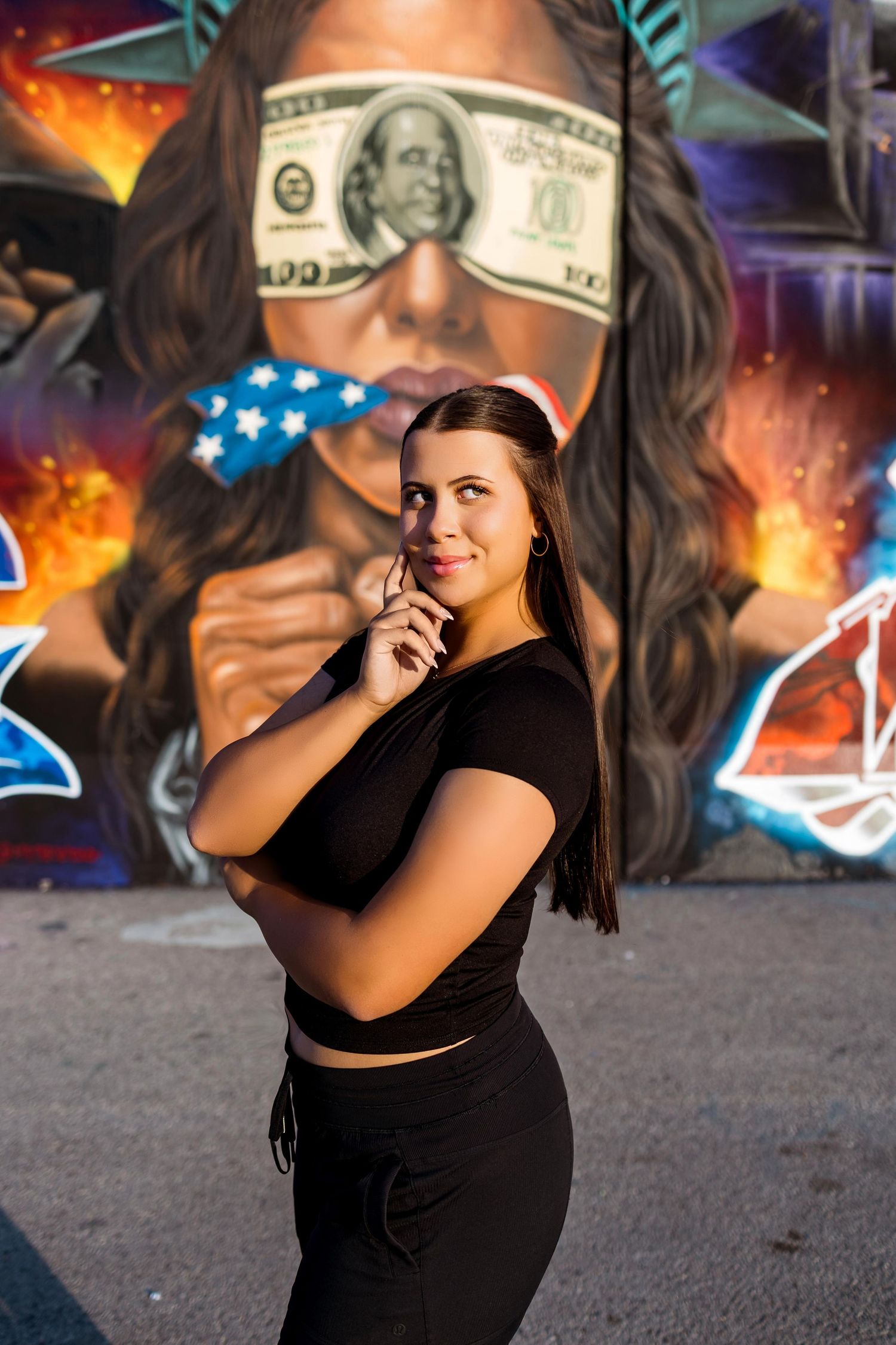 Urban photoshoot against colorful graffiti wall with money and star props.