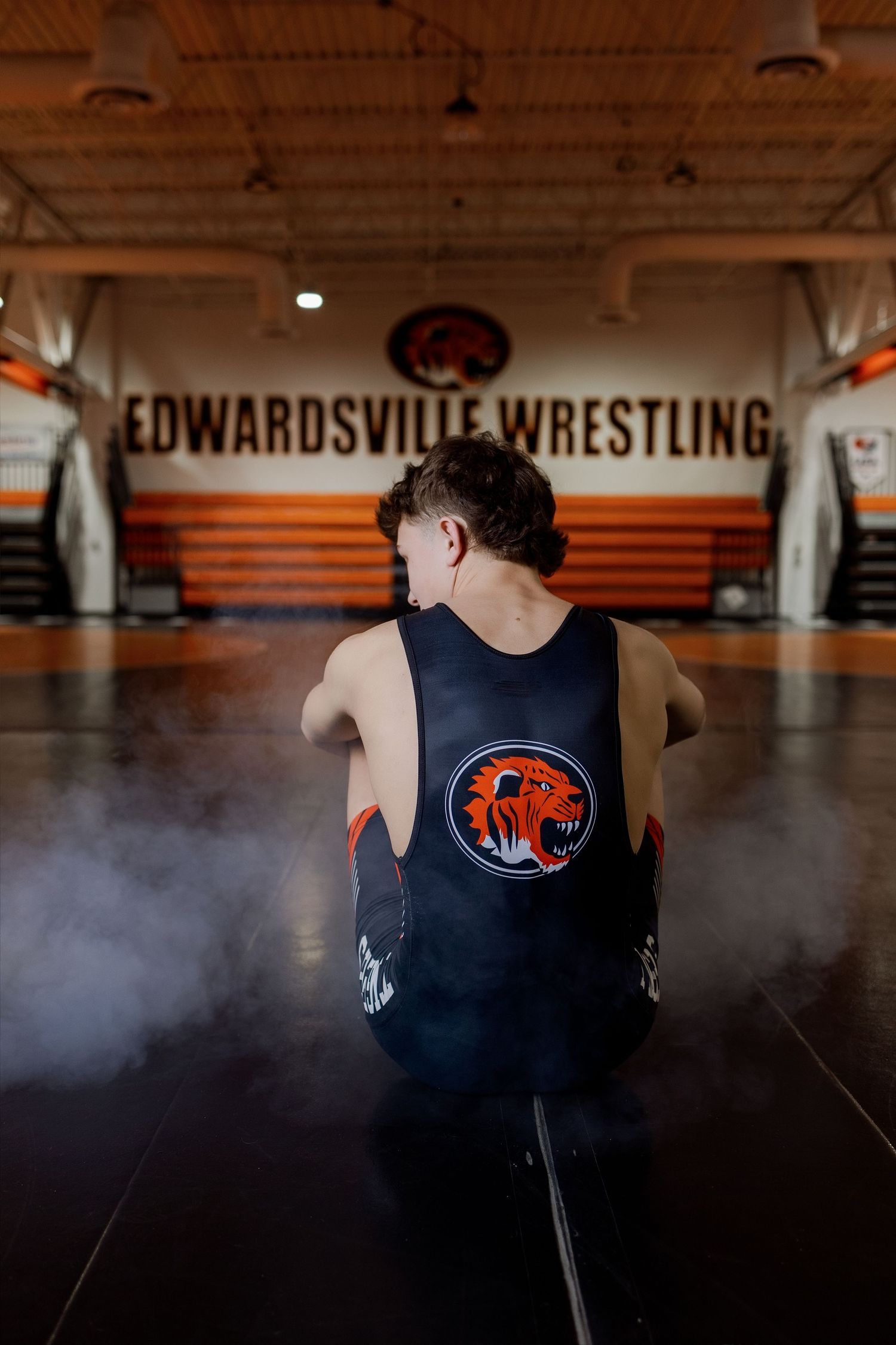A series of photos showing wrestling practice at Edwardsville Wrestling facility with dark uniforms and orange lighting.