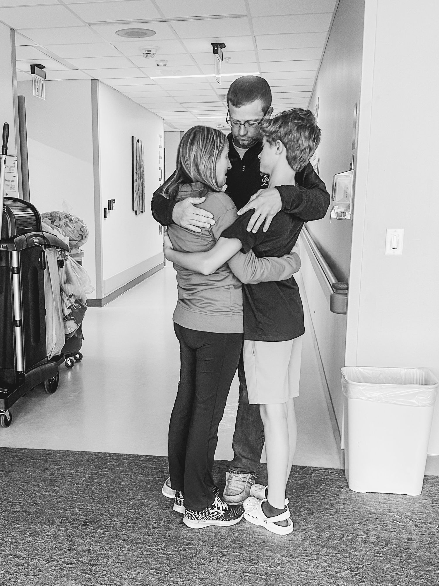 Emotional family embrace in hospital hallway showing support and love.