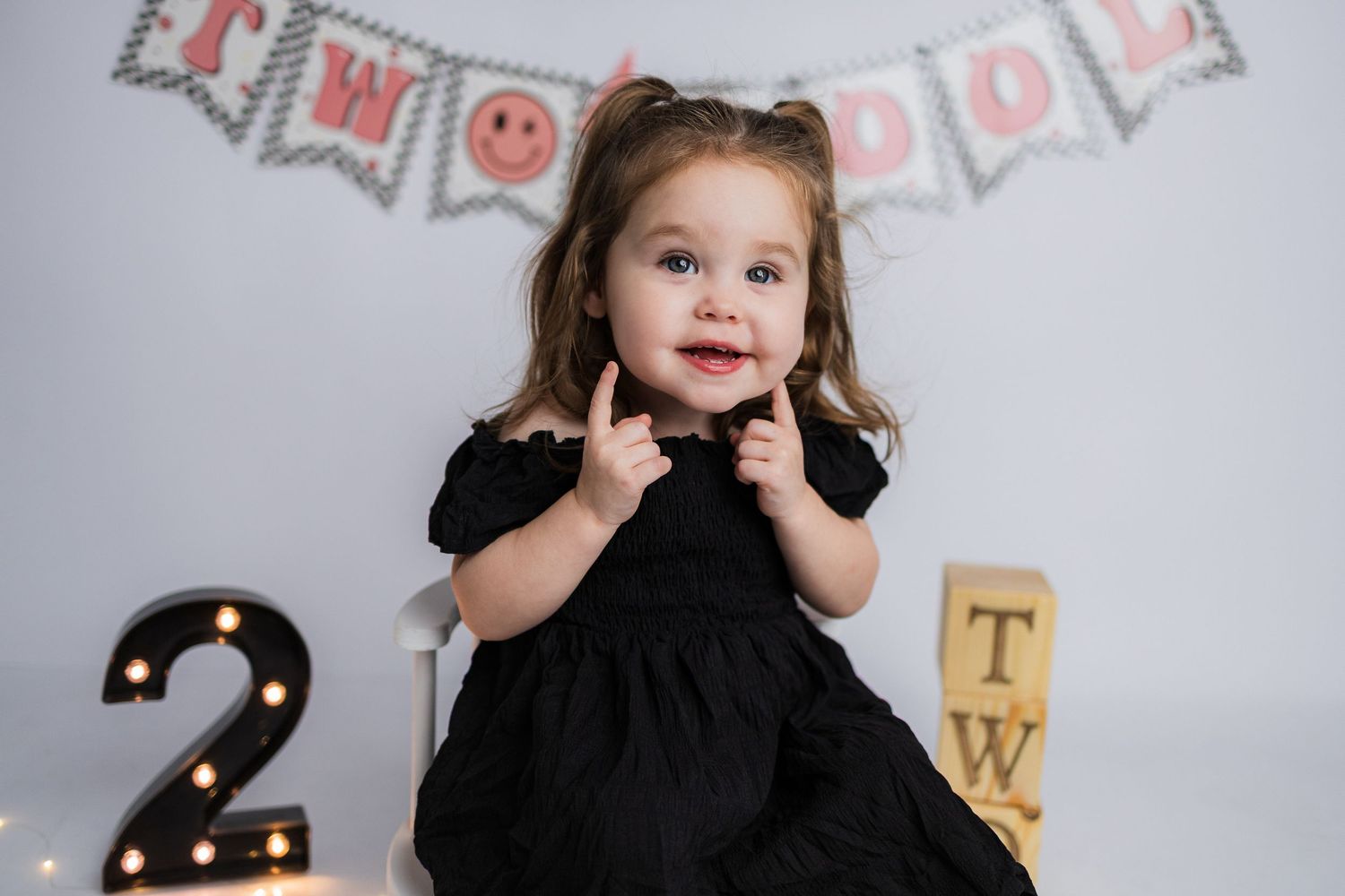 A birthday celebration setup showing a silver number 2 balloon against a white backdrop with festive bunting decorations.