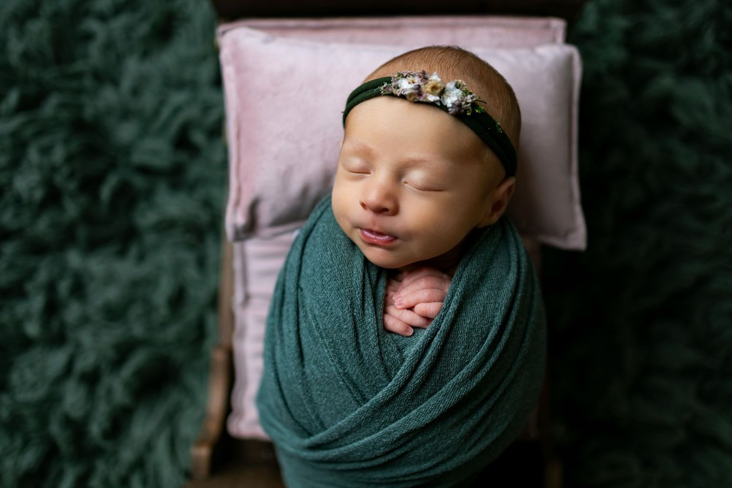 A collection of newborn photography portraits showing a sleeping baby wrapped in dark green fabric with floral headpiece.