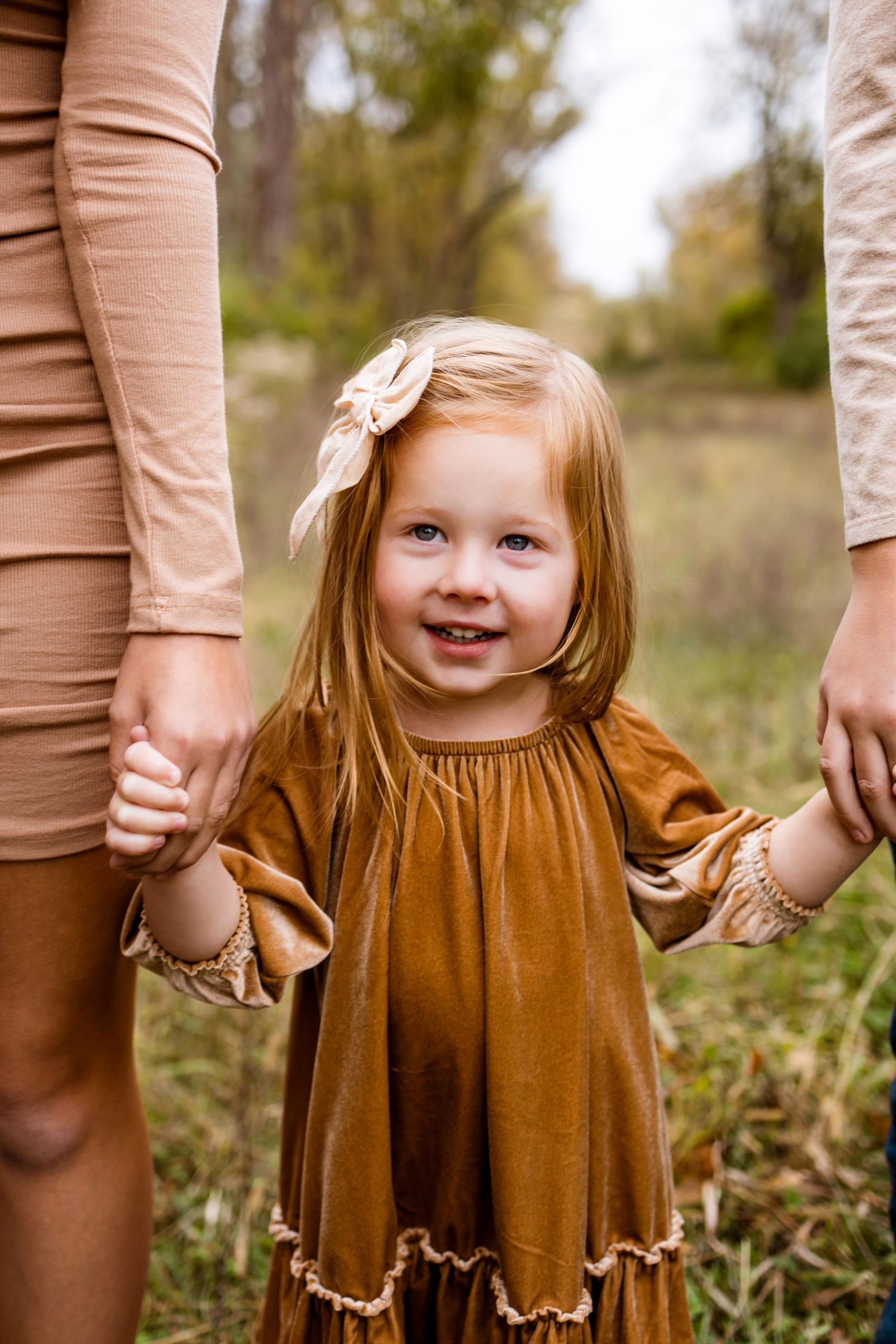 A series of four connected photos showing a small child in a brown dress holding hands with someone in beige clothing.