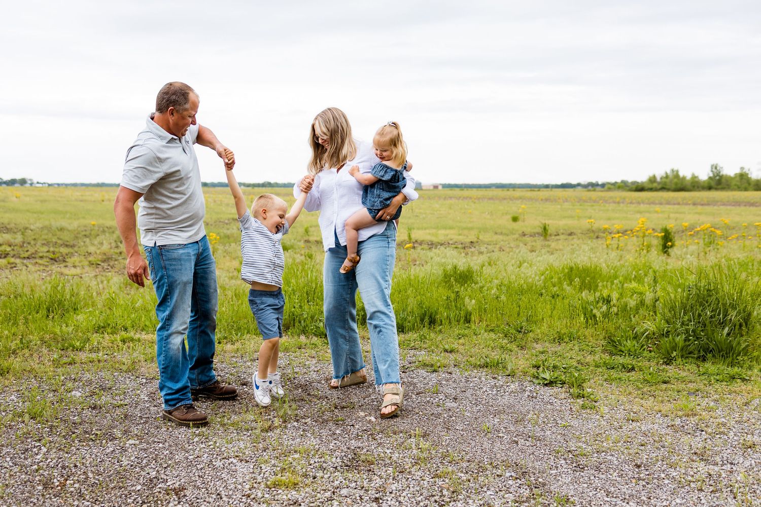 A family of four enjoys quality time together in an open field on a sunny day.