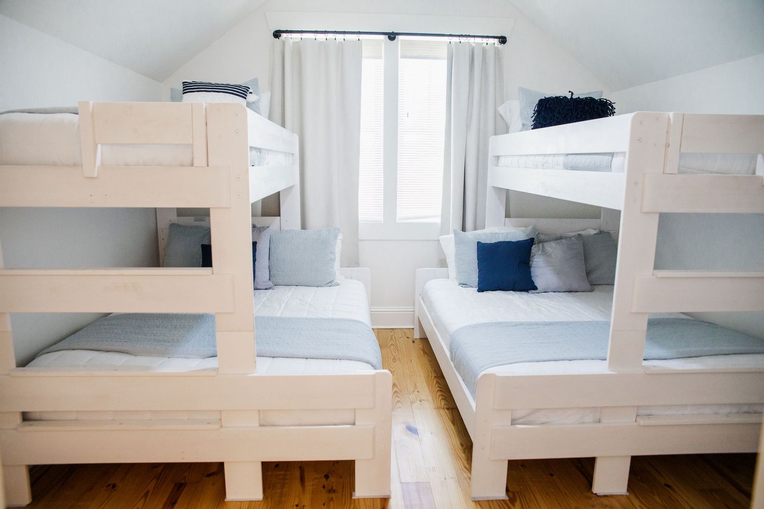 Modern white bunk beds with blue and gray bedding in a bright coastal-themed bedroom.