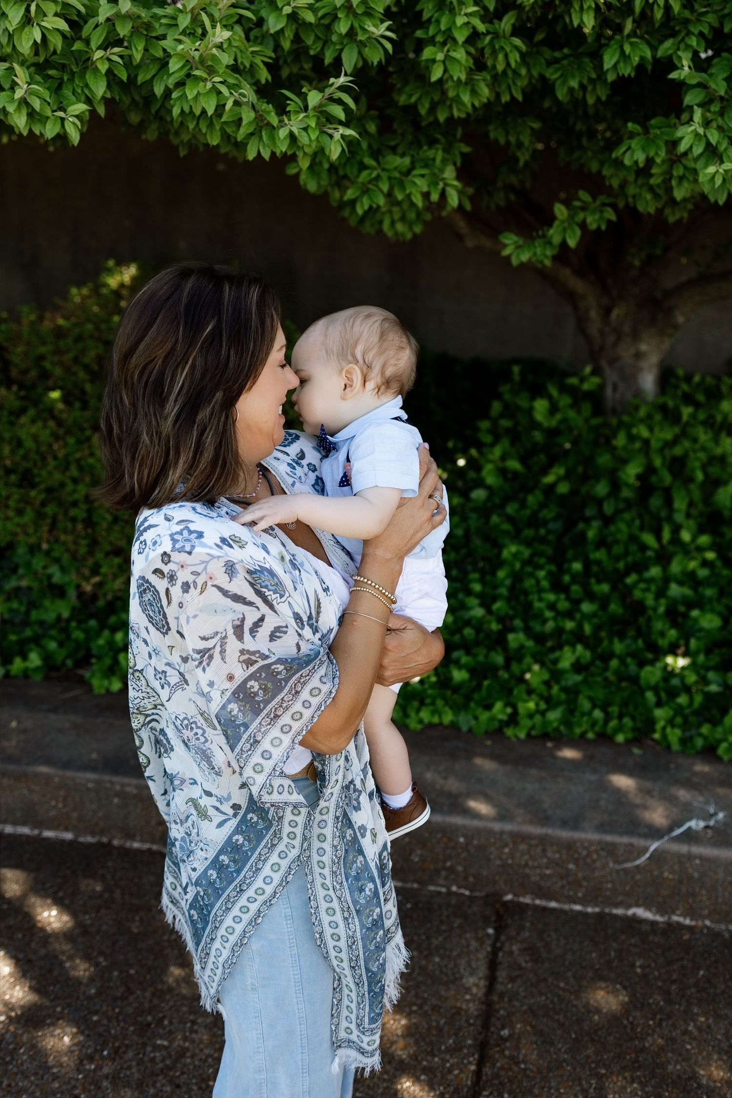 Woman holding and kissing a baby during a candid outdoor family portrait near Edwardsville