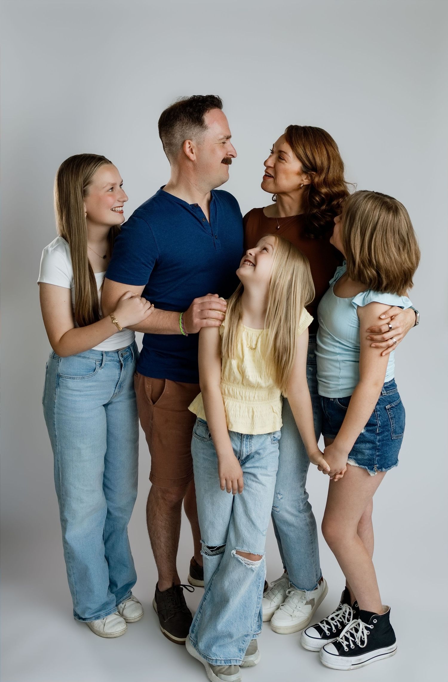 Parents and their three daughters laughing together during a relaxed studio family portrait at TLP