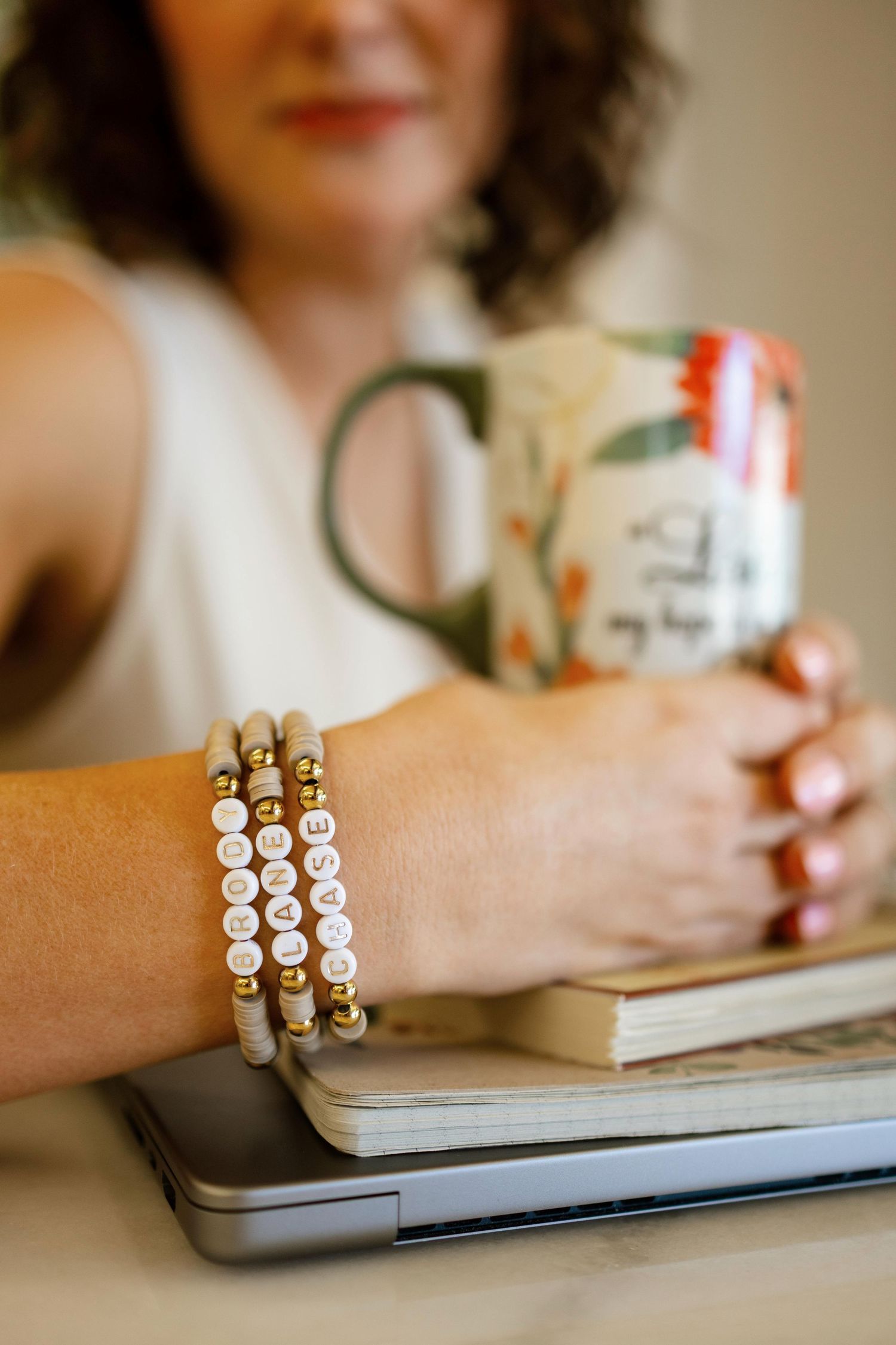 Close-up of stacked beaded bracelets on wrist while working at laptop.
