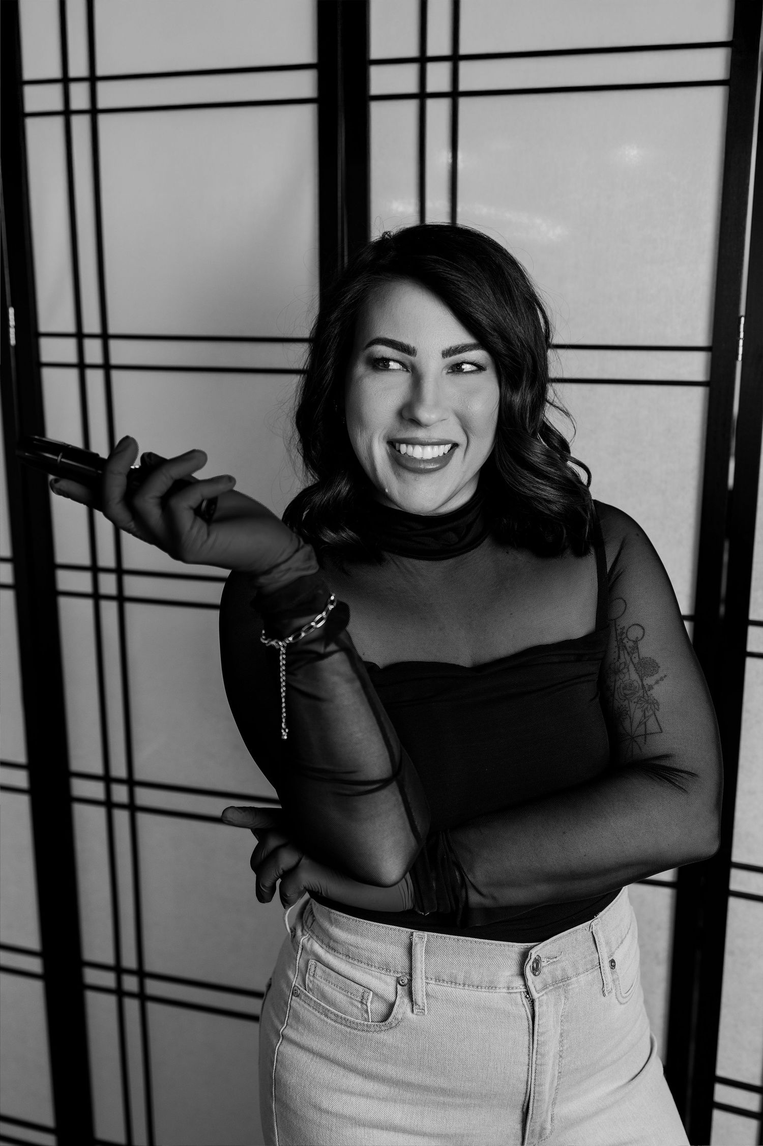 A black and white photo series showing a person in a sheer black top and light pants posing playfully against a wall.