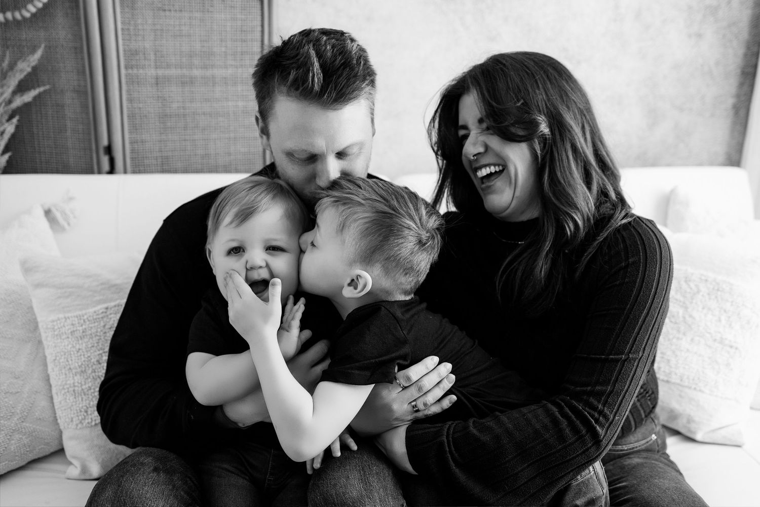 Black and white photo collage showing intimate family moments of laughter and affection between parents and children.
