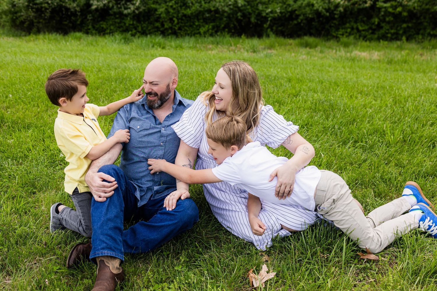Family sharing joyful laughter while relaxing together on green grass.