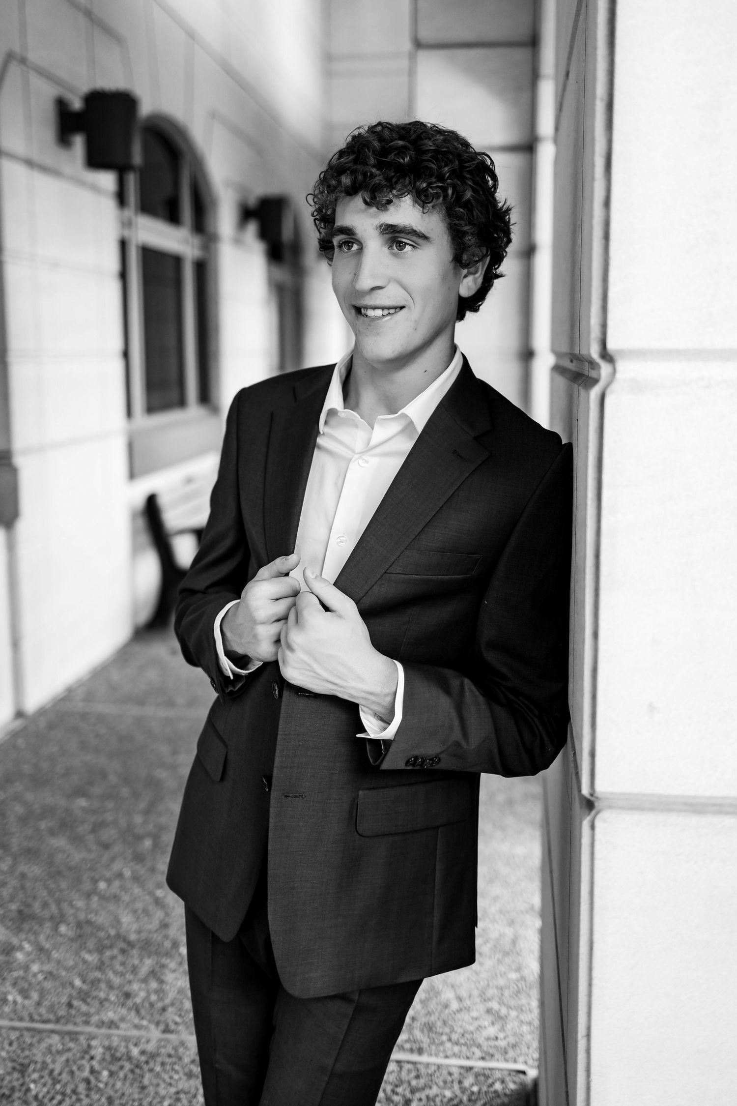 A series of black and white portraits showing someone in a formal suit posing against a white column background.