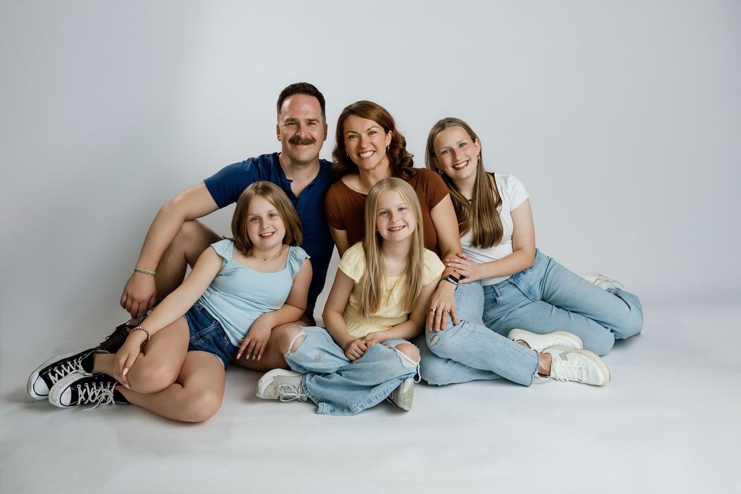 Family of five posing together during a relaxed studio personality photography session at TLP