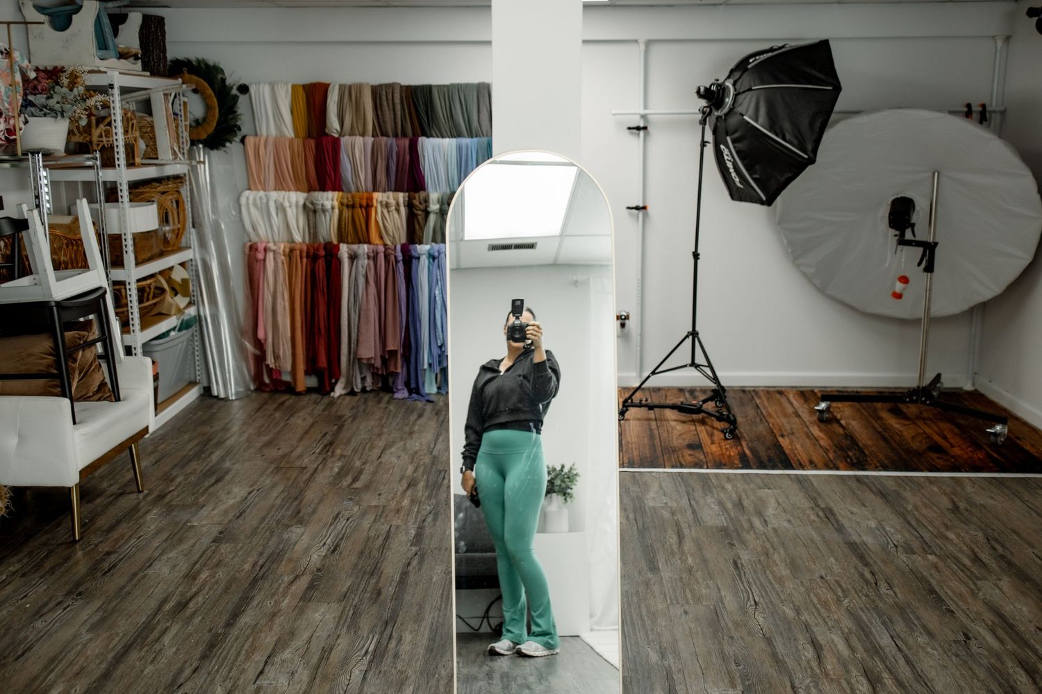 A photography studio interior with wooden floors, white walls, and professional lighting equipment set up.