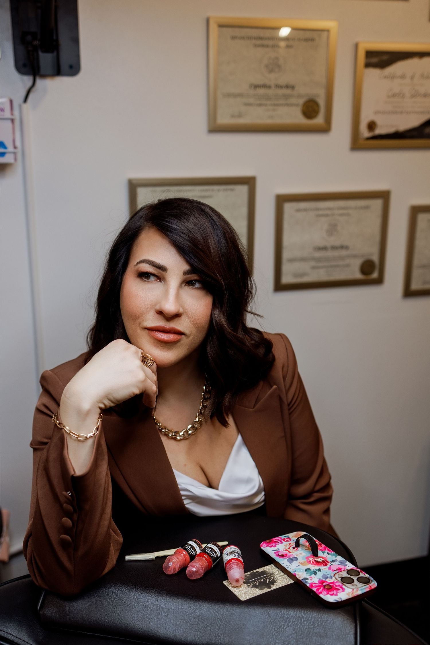 Professional portrait series showing relaxed poses against wall with framed certificates in brown tones.