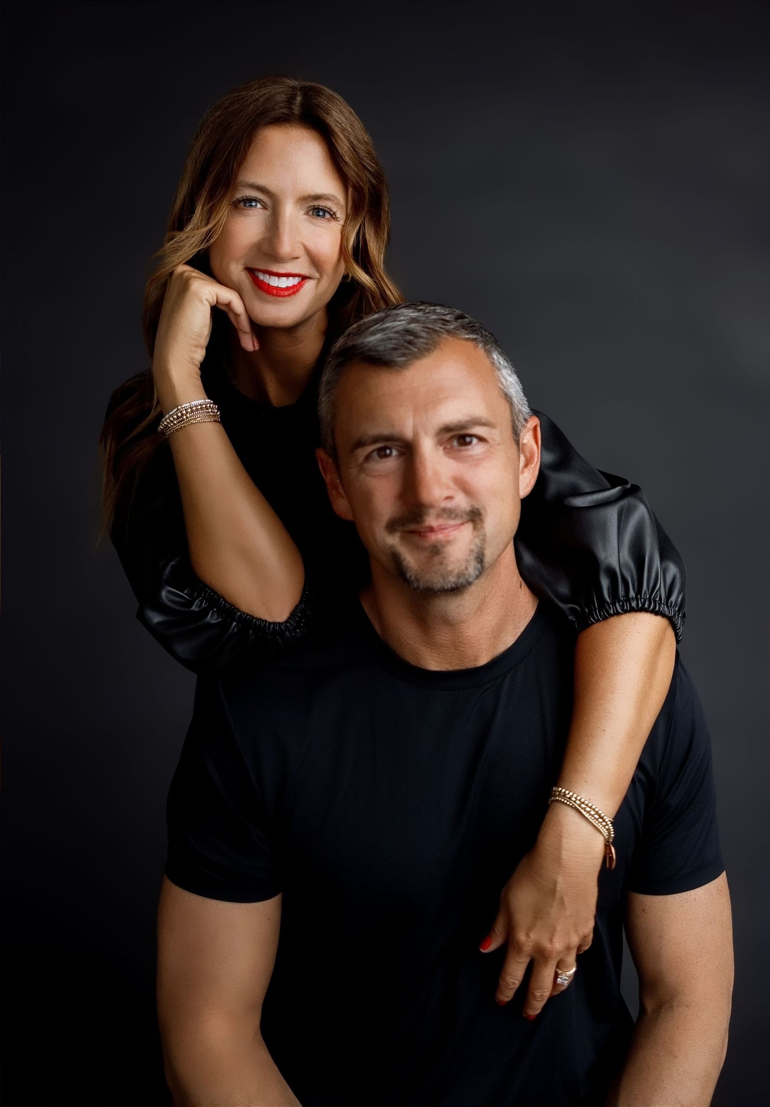 Podcasting couple wearing coordinated black outfits during a dramatic personal-brand photography session in Edwardsville