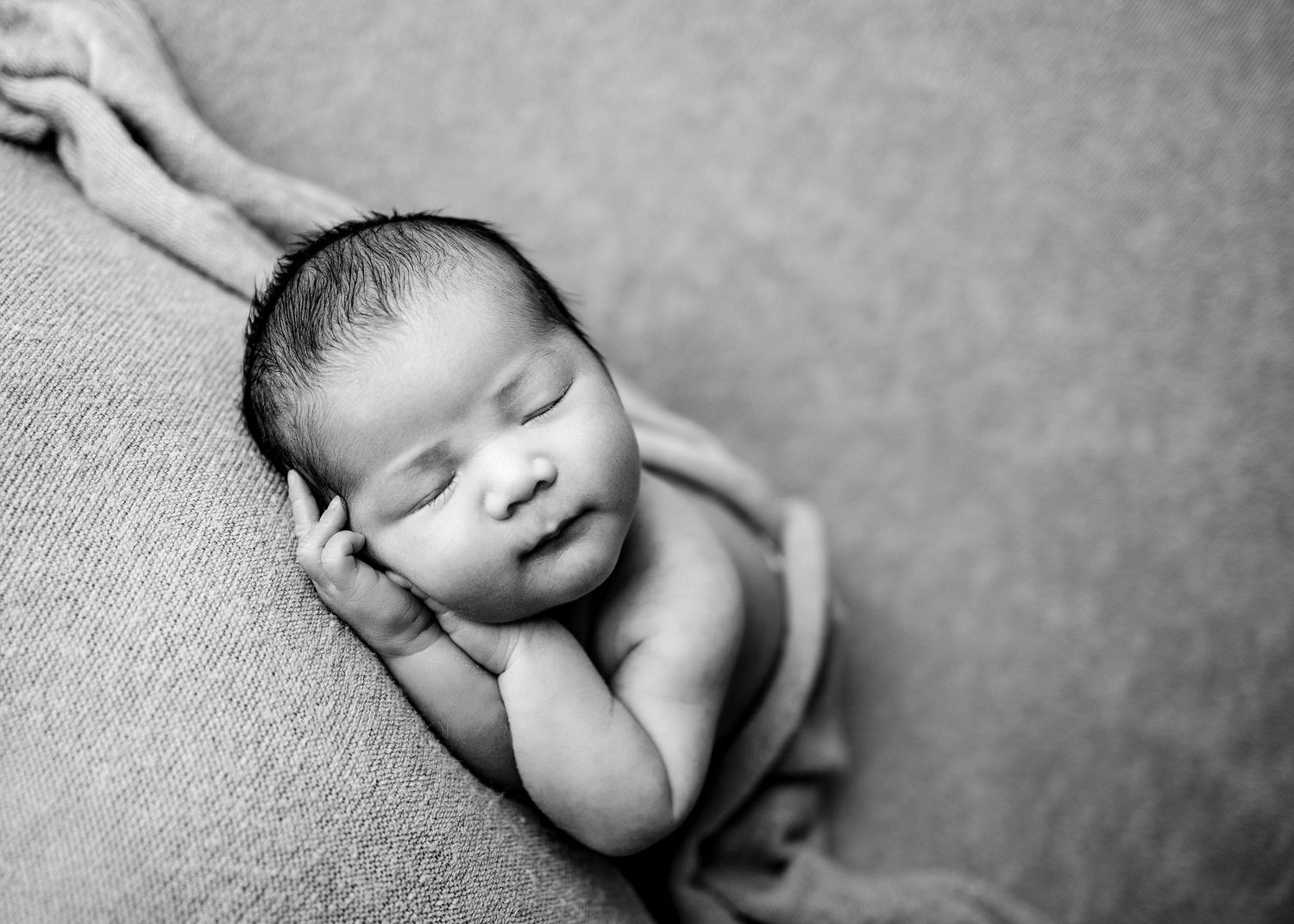 A series of black and white newborn baby photos showing peaceful sleeping poses in artistic composition.