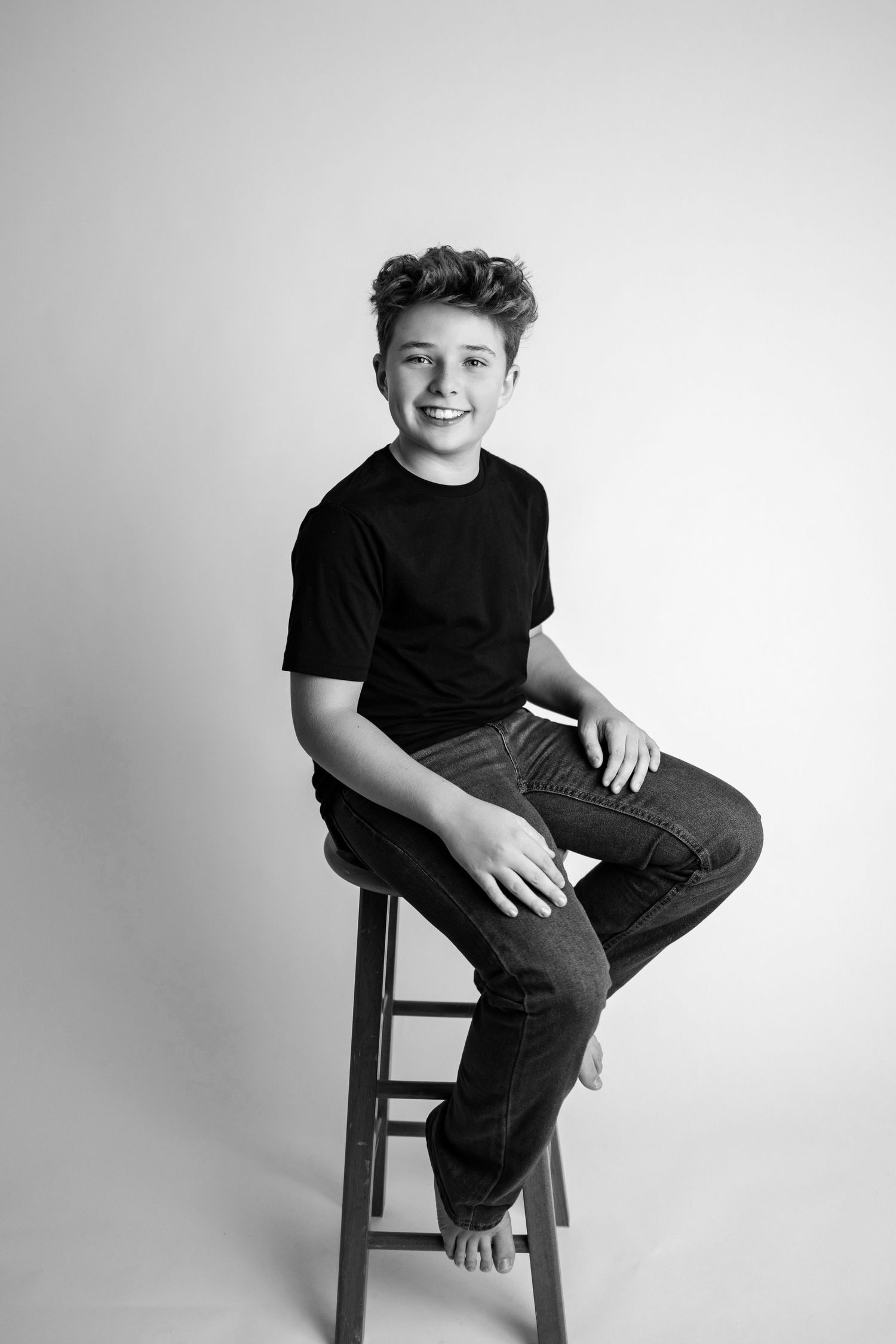 A black and white photo series showing someone sitting on a wooden chair in various casual poses against a plain backdrop.