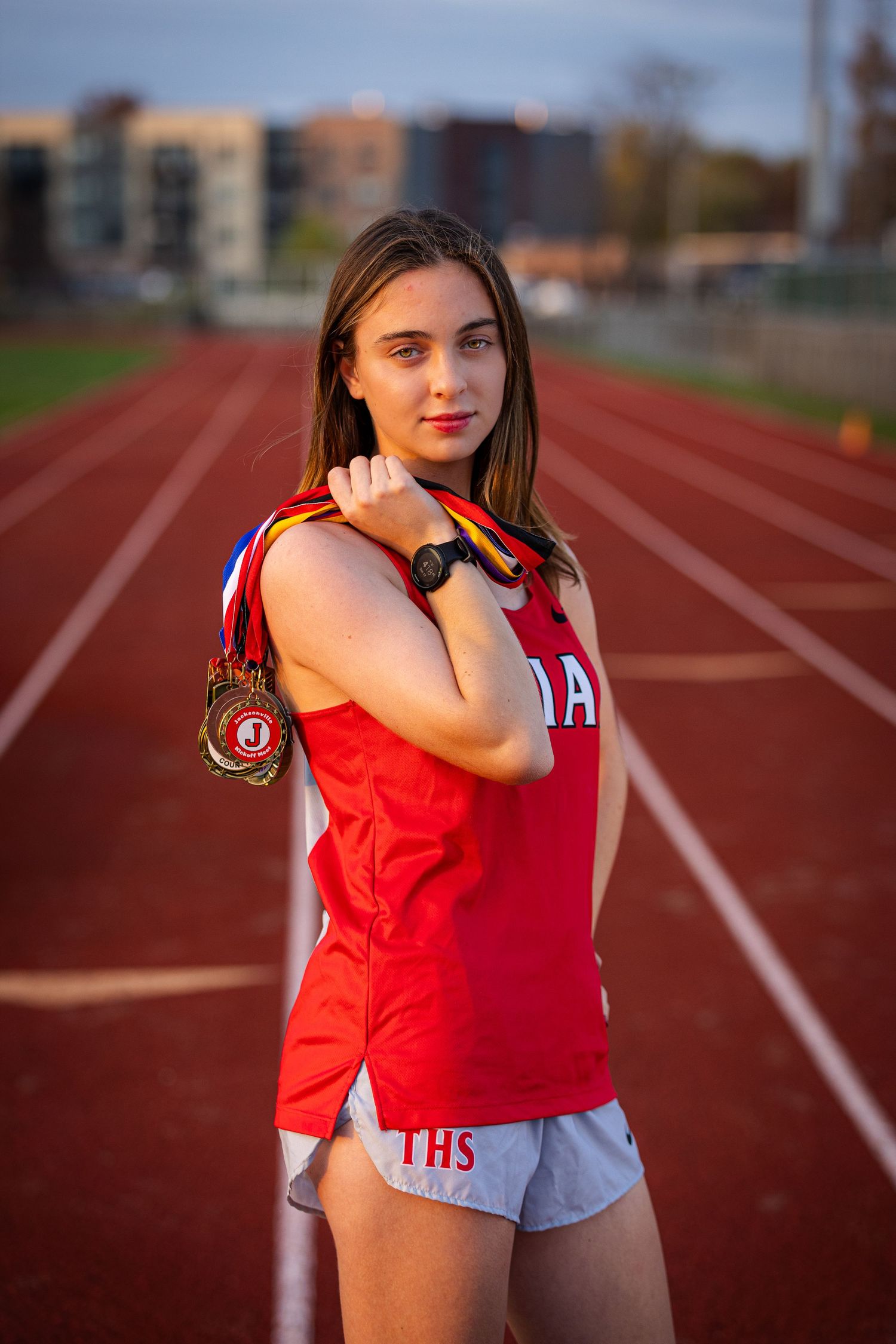 Athletic shot on running track displaying medals at golden hour.