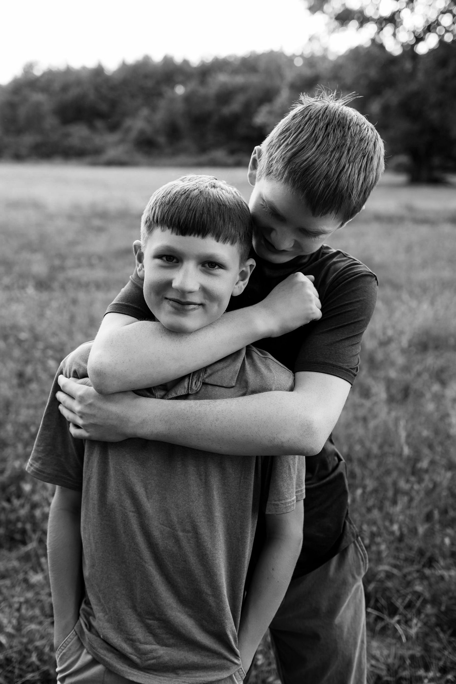 Black and white photo sequence showing two people embracing in a grassy field.