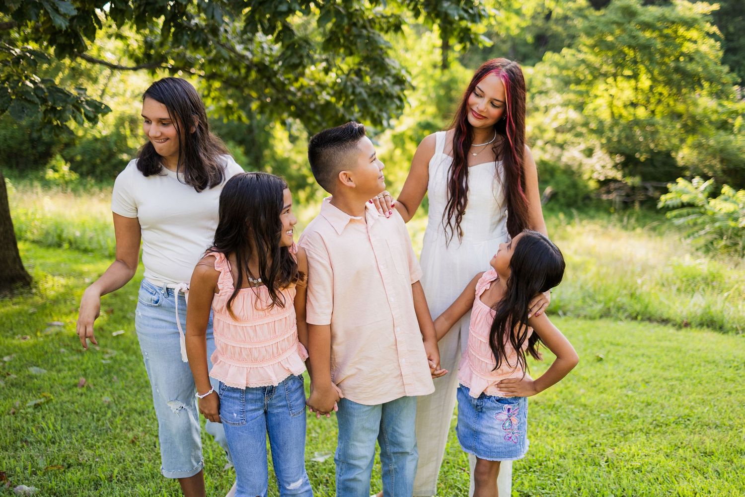 A group of people standing together in a verdant outdoor park setting during a sunny day.