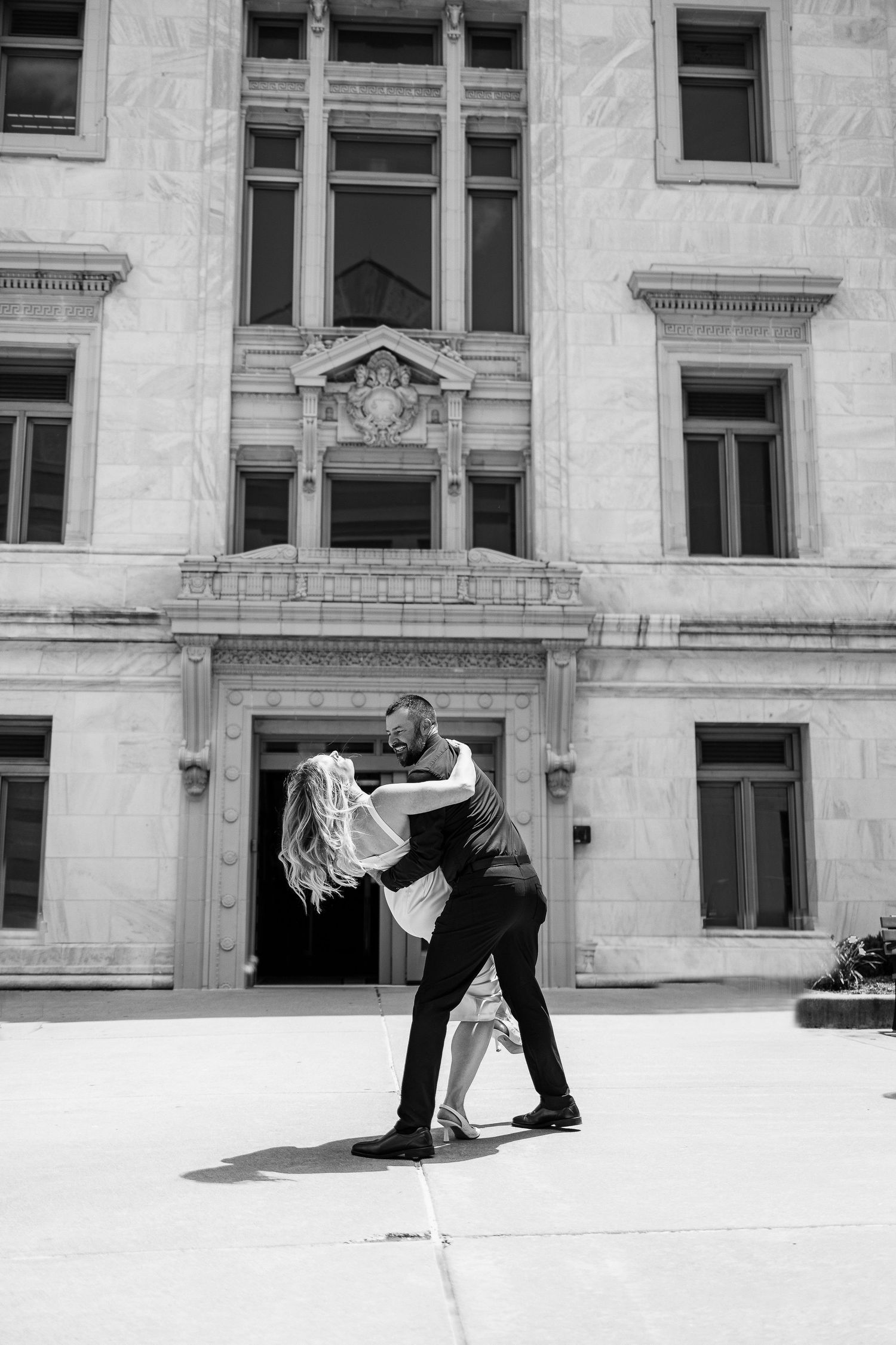 A black and white triptych of dancers in motion against a classic architectural backdrop with white stone walls.