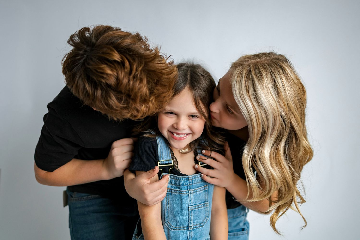 A series of intimate family photos showing parents embracing and kissing their young child in casual clothing.