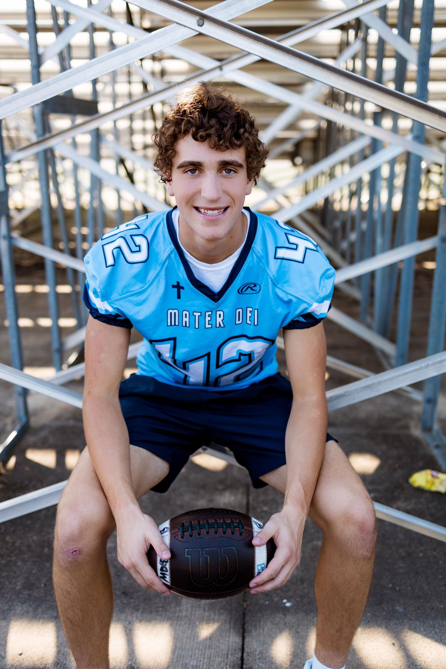 Football player in light blue jersey sits on bleachers holding ball in multiple similar poses.