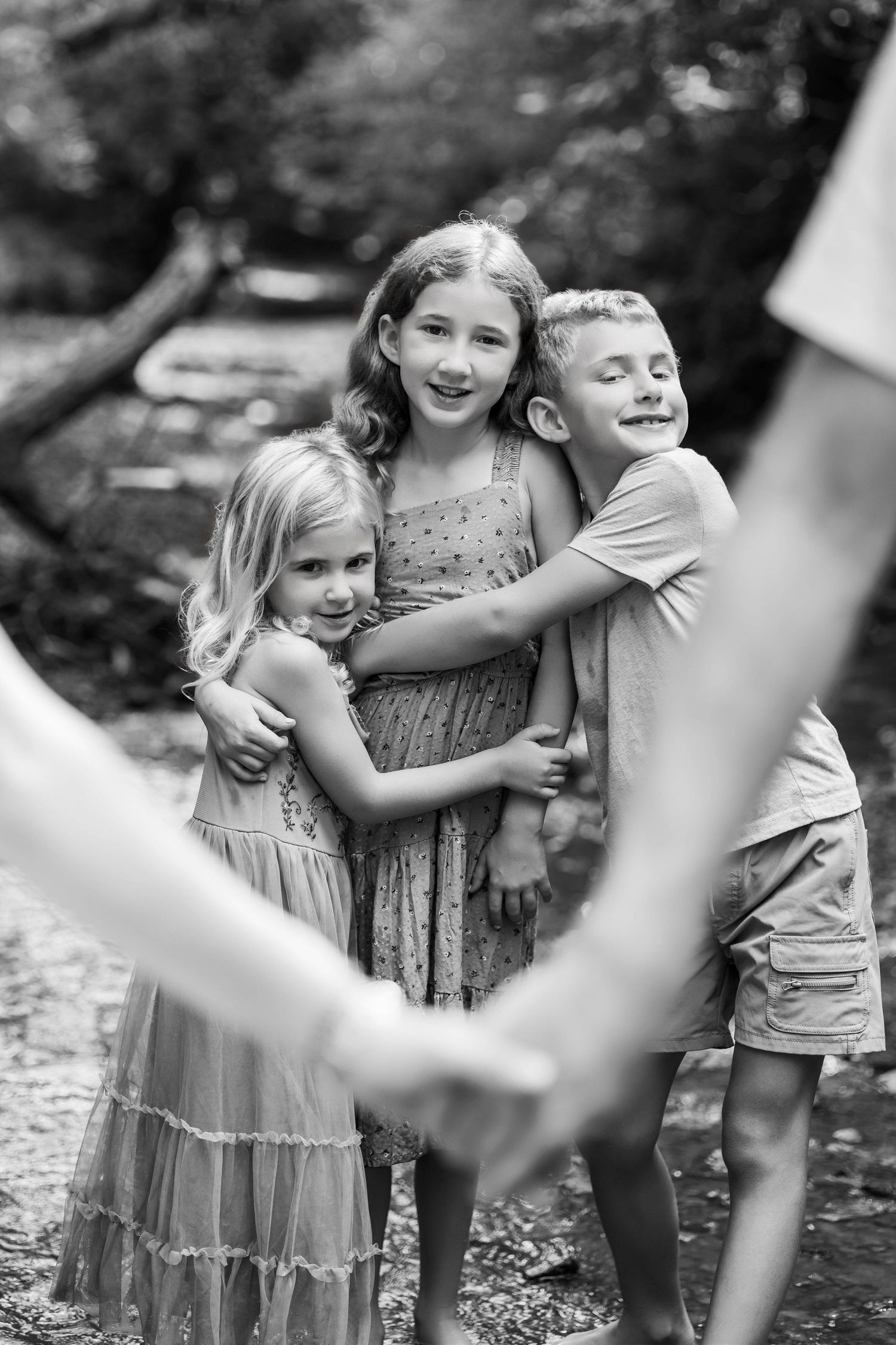 Three children playing and laughing together outdoors in a candid black and white photo series.