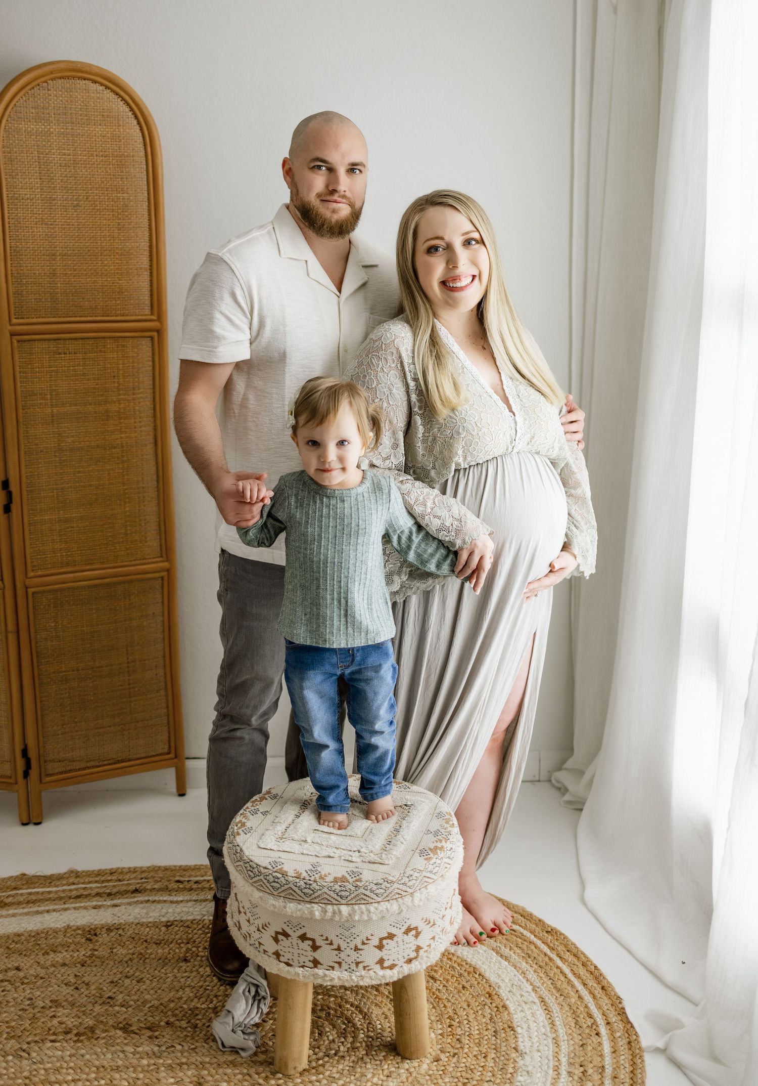 Family maternity photo session with vintage-style decor and natural lighting in a bright studio setting.