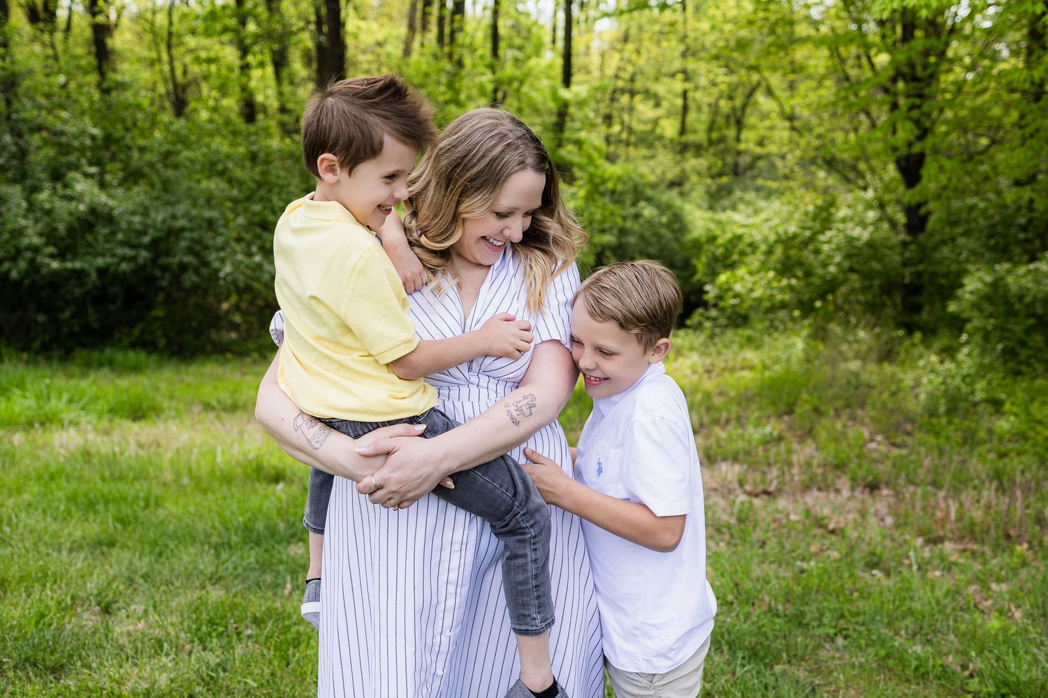 Group embracing in a tender moment outdoors surrounded by lush green trees.