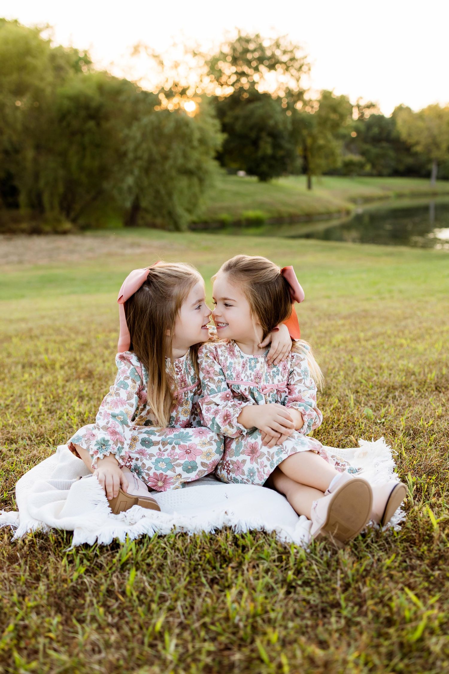Candid moments captured on a blanket in a sunny field during a lifestyle photography session.