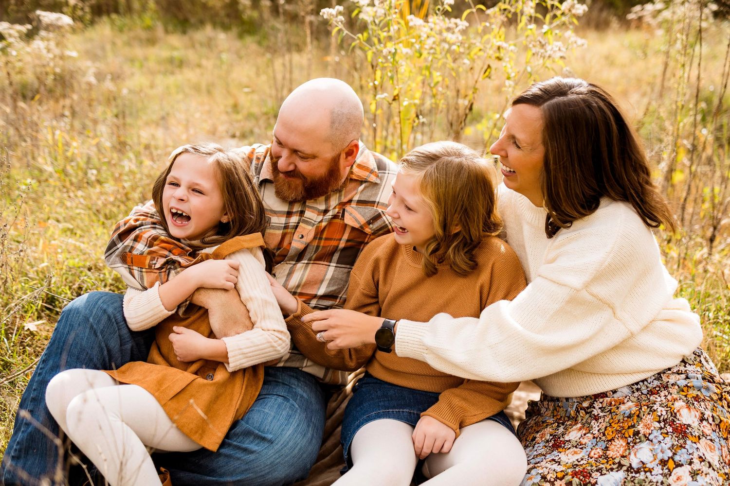 Family enjoying quality time together outdoors in a sunlit meadow during fall season.