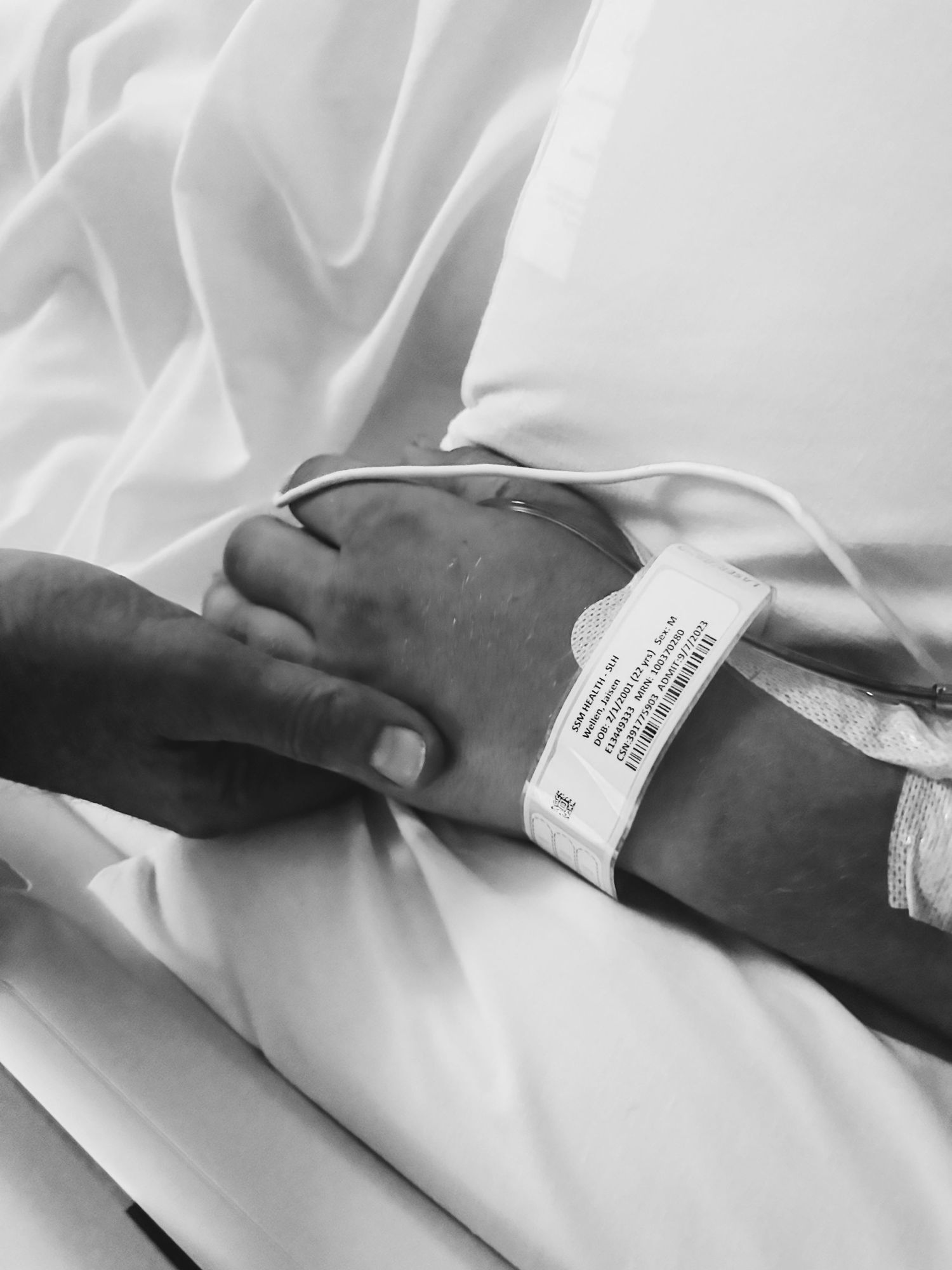 Close up of hospital identification bracelet on arm against white bedding.