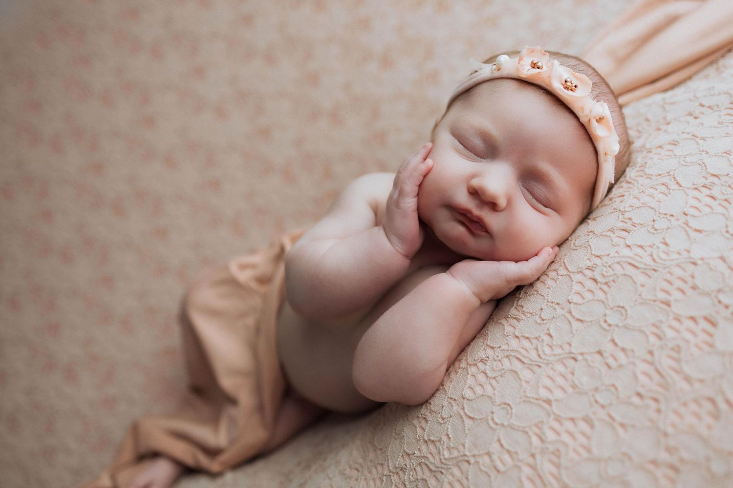 A newborn baby sleeps peacefully on textured beige fabric in a series of connected artistic portraits.
