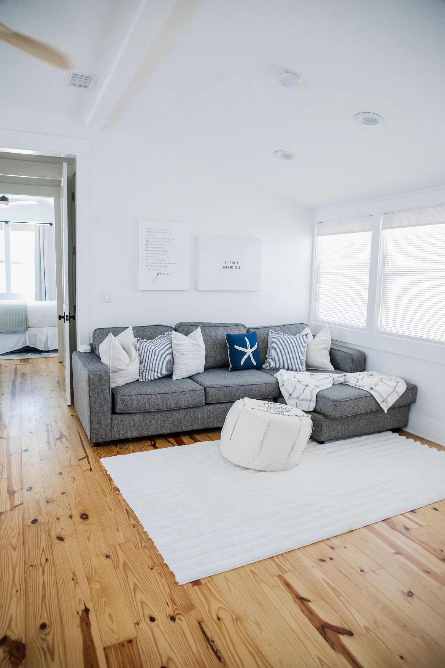 Modern living room with grey sectional sofa and white area rug on wooden floors.