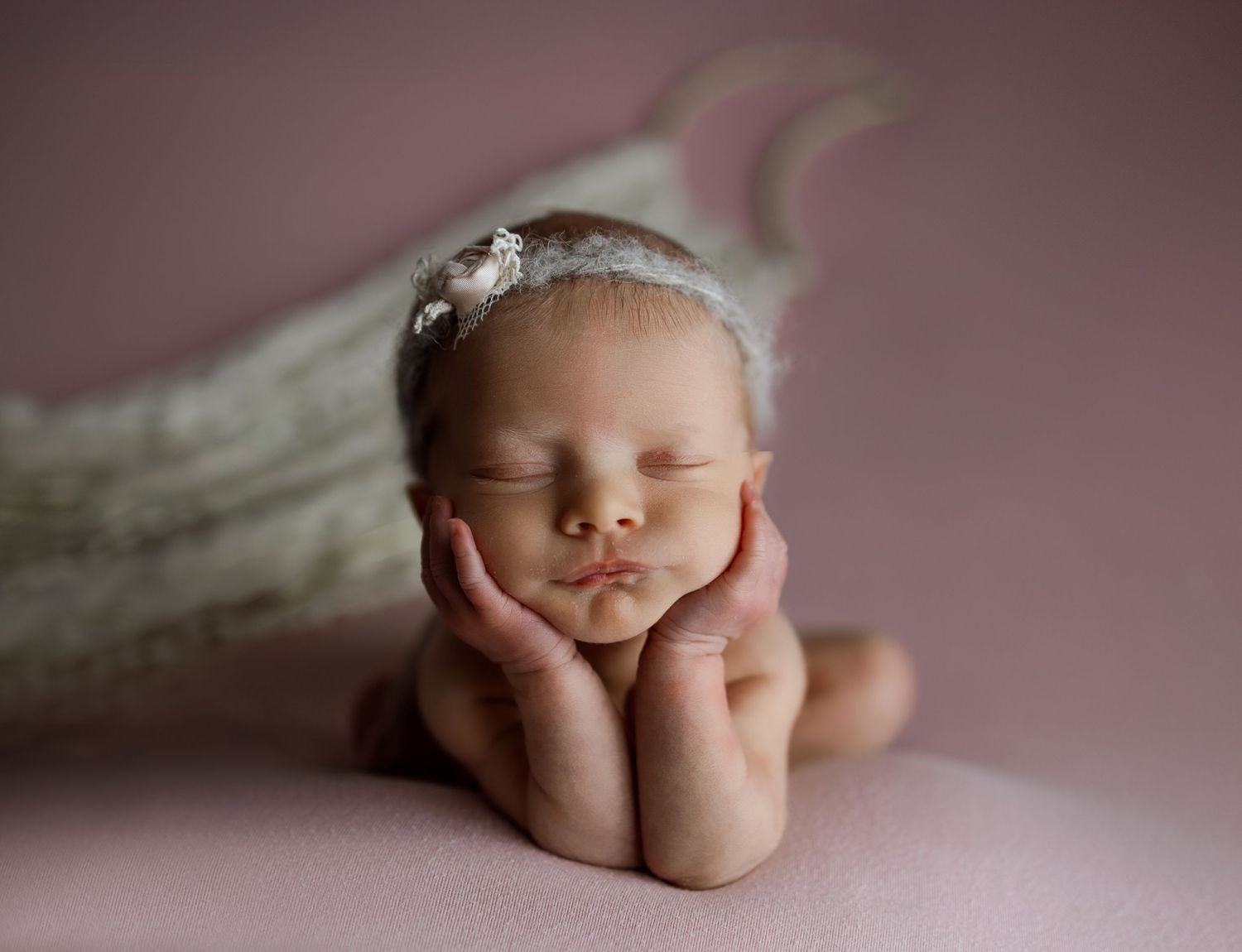A collage of newborn baby photos showing tiny hands, feet, and sleeping poses against a soft pink background.