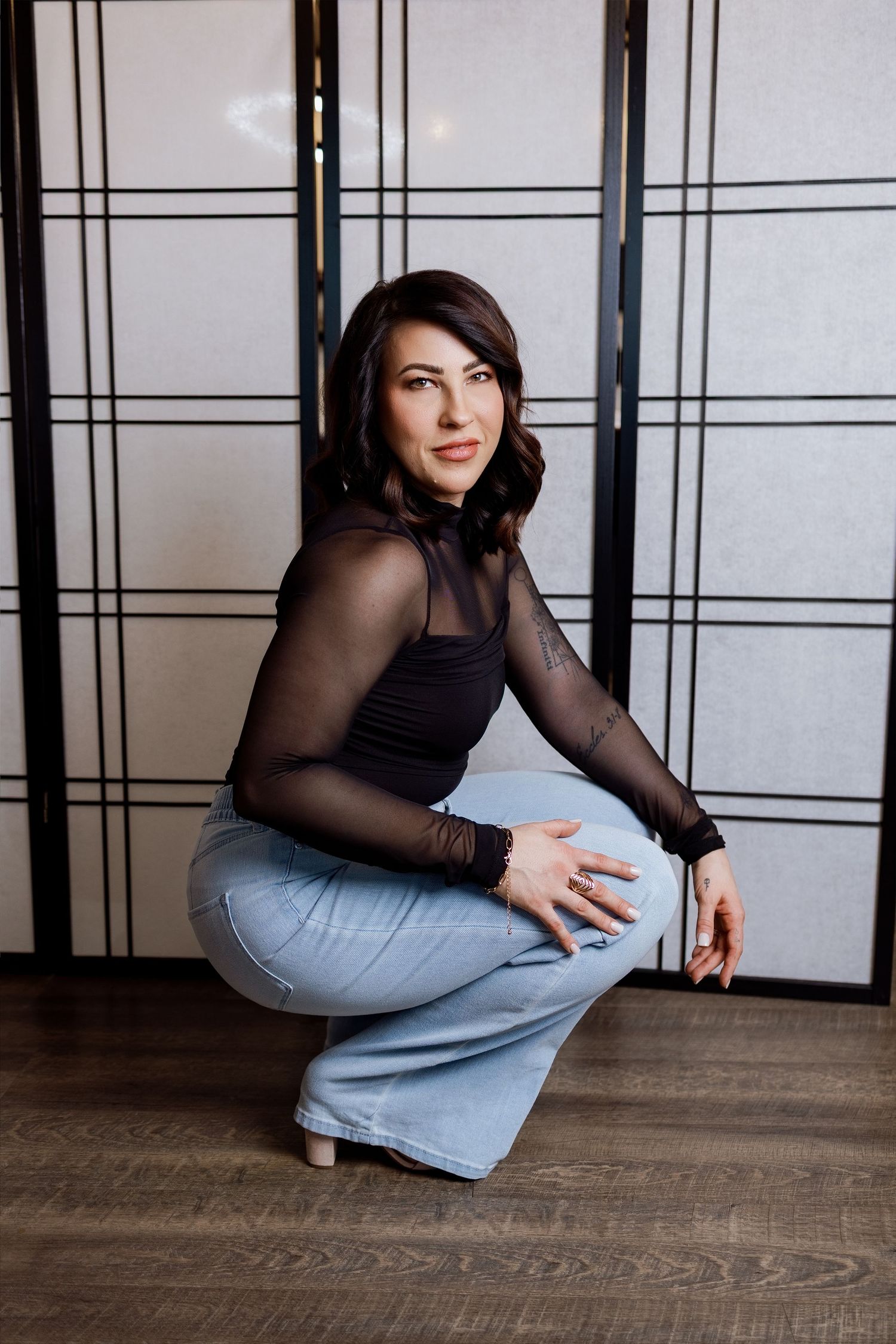A woman in a black mesh top and light jeans poses against a wall in a series of artistic dance-inspired movements.