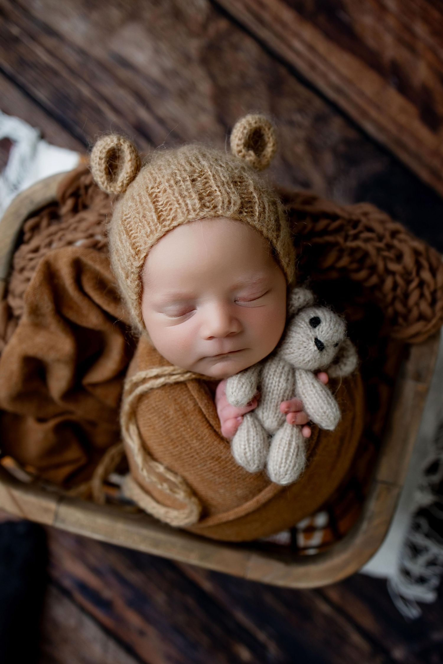 A series of cozy newborn photography shots featuring soft brown knit accessories and a small stuffed toy elephant.