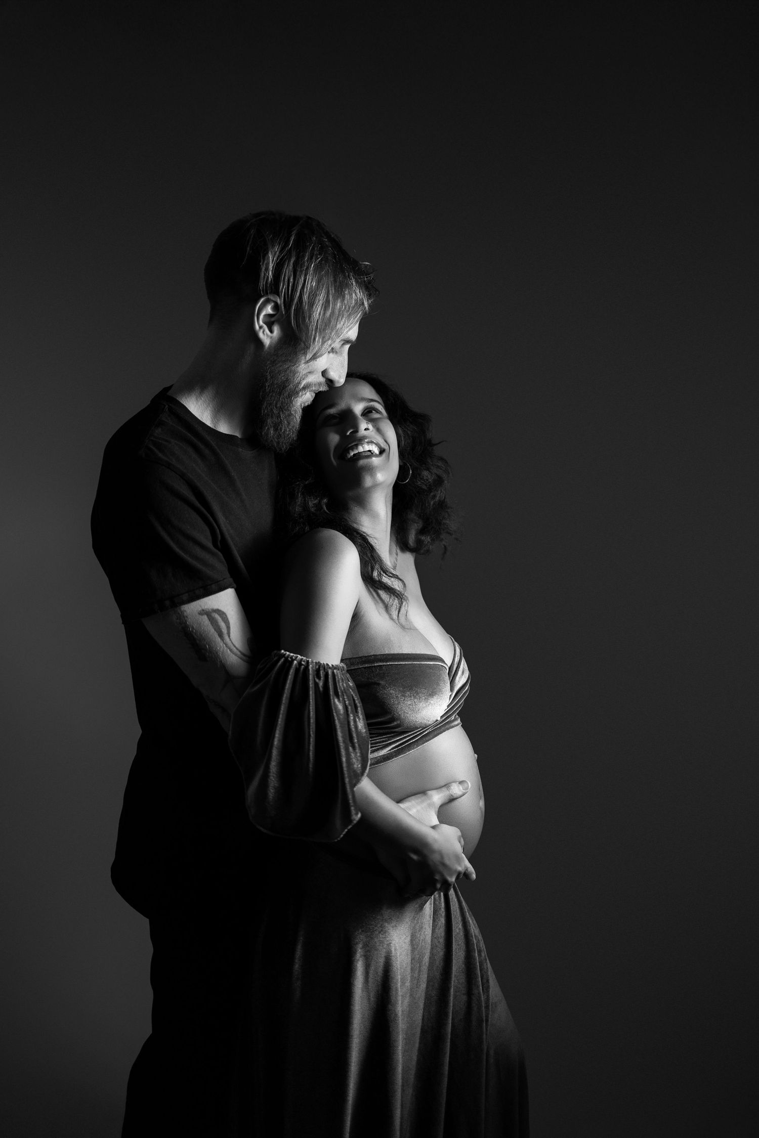Black and white intimate maternity portraits showing tender moments in dramatic lighting.