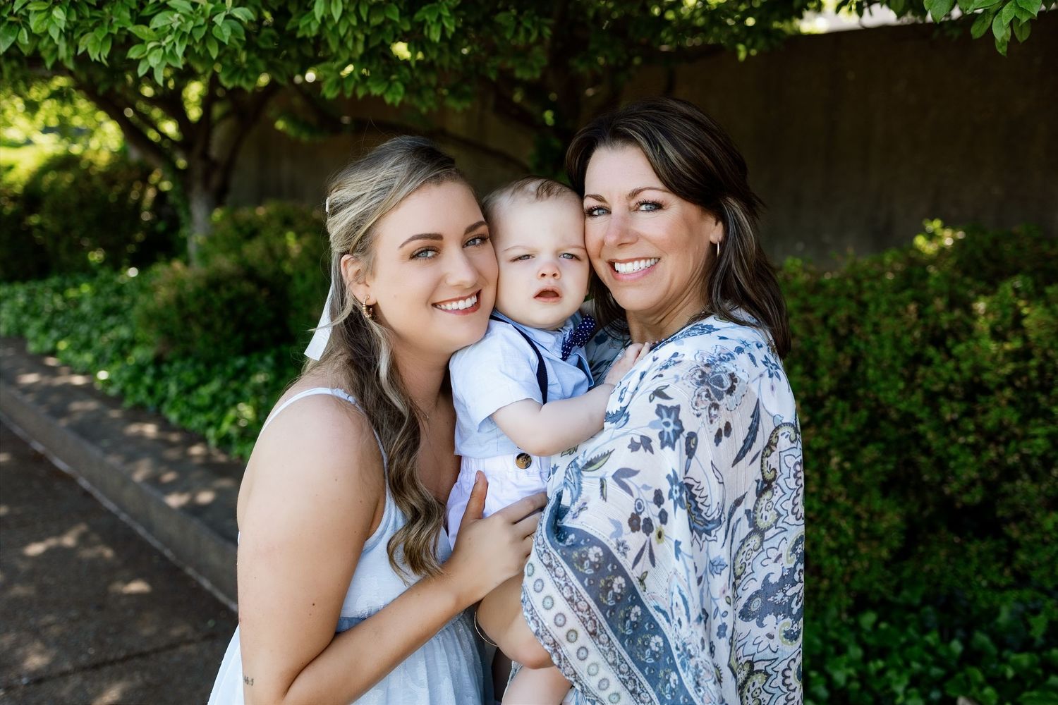 Two women cuddling a baby boy during an outdoor multigenerational family photography session