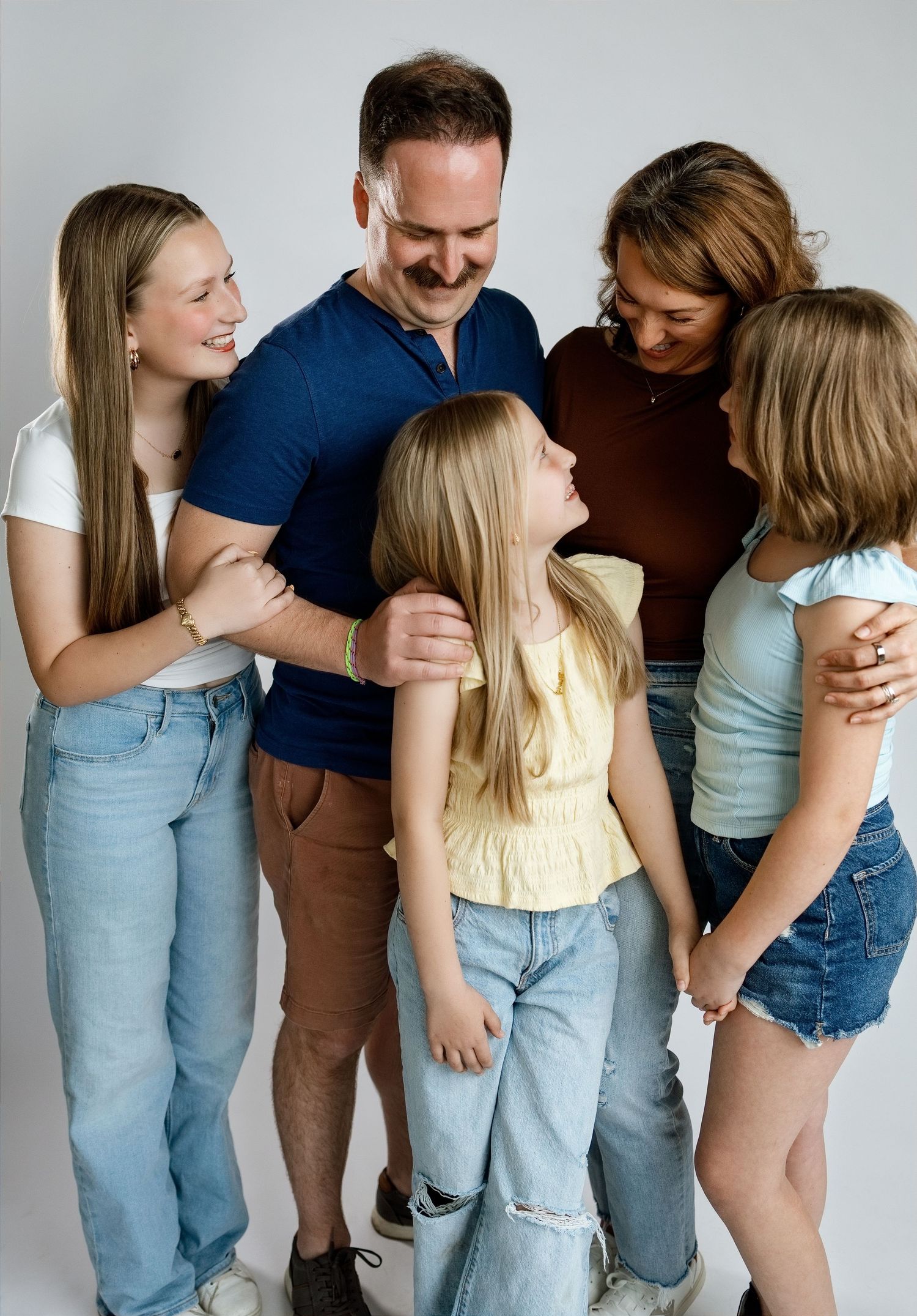 Family of five sharing a group hug during a personality-filled studio photography session in Edwardsville