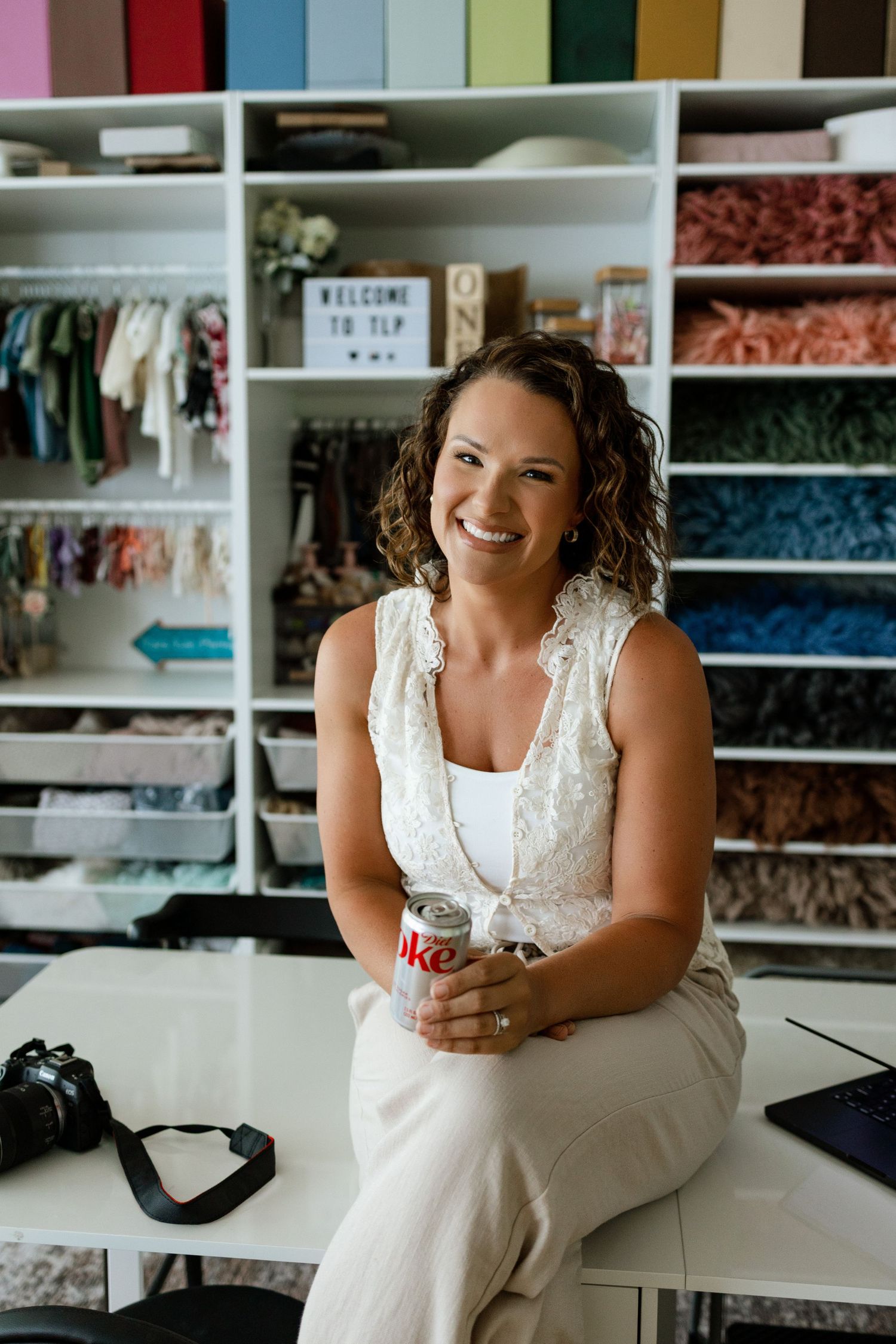 Tara enjoying a Diet Coke while seated beside the colorful prop collection in her Edwardsville photography studio