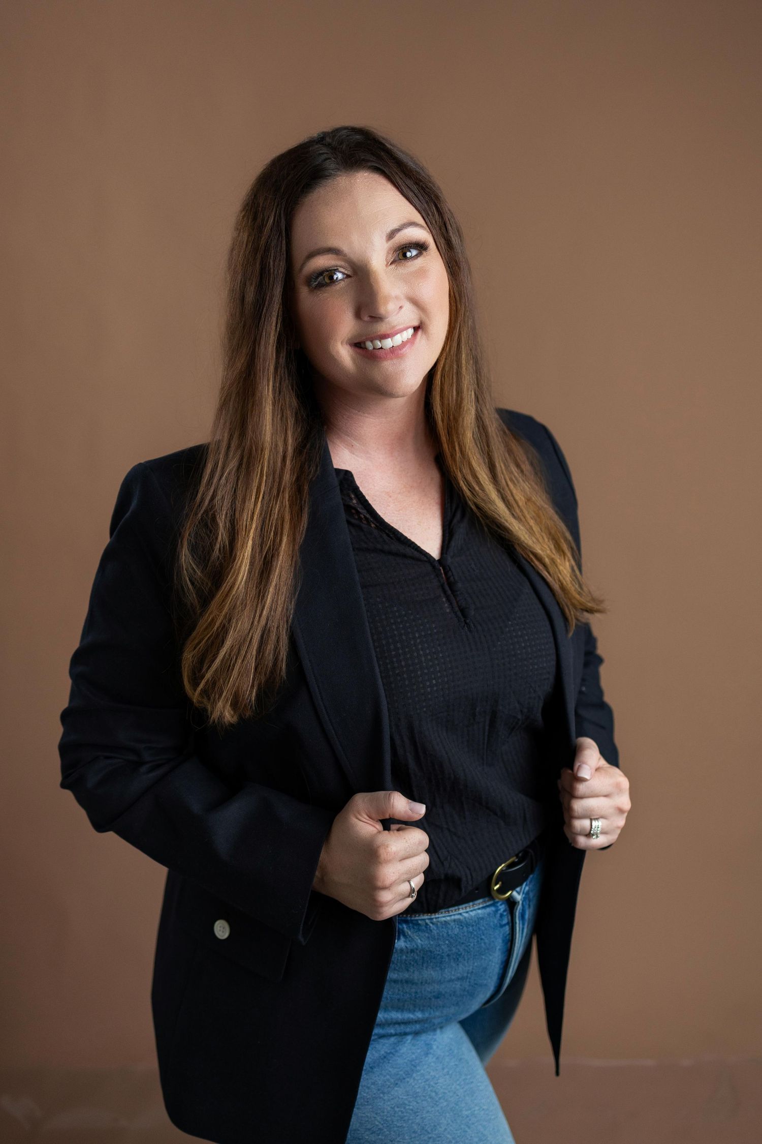 Creative headshot series with various expressions in dark blazer against warm brown backdrop.