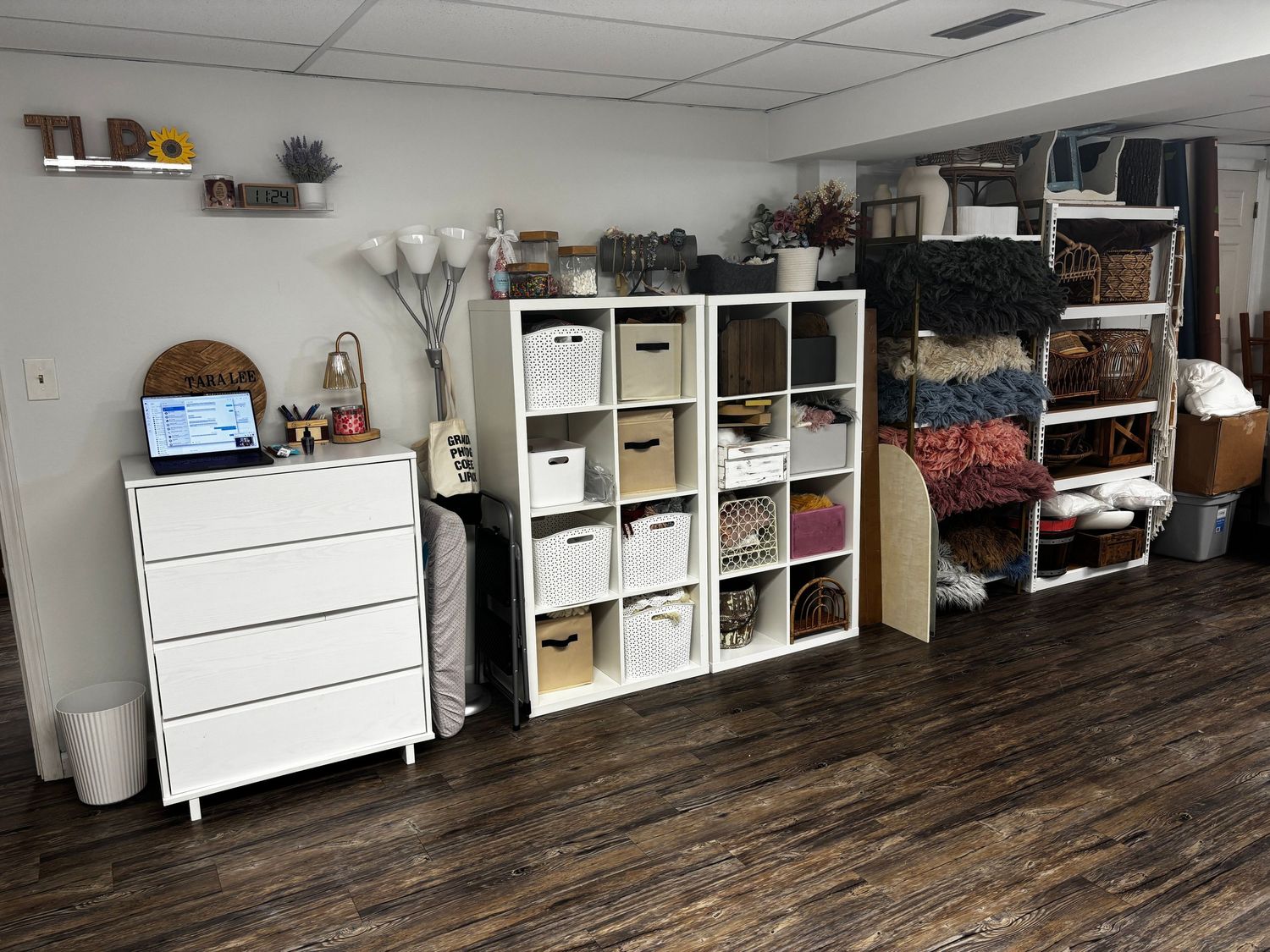 White storage cabinets and shelving units line the walls of a room with rustic wood flooring.